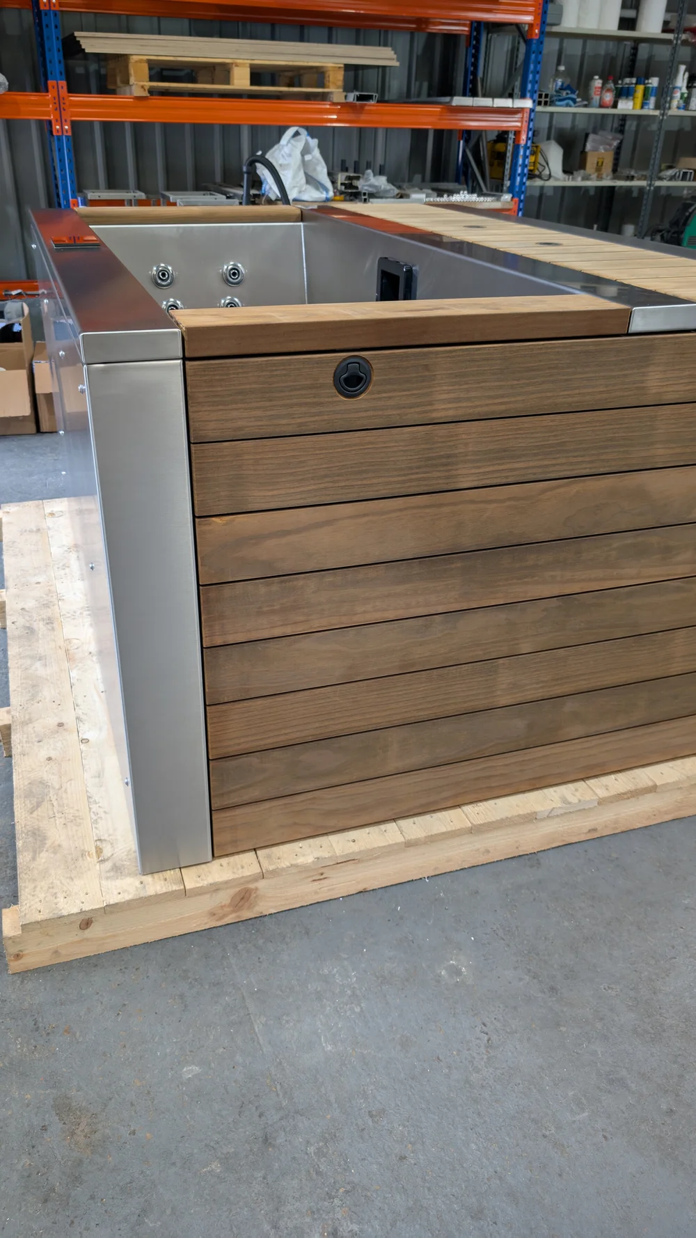 A partially assembled tub with timber cladding and stainless interior.