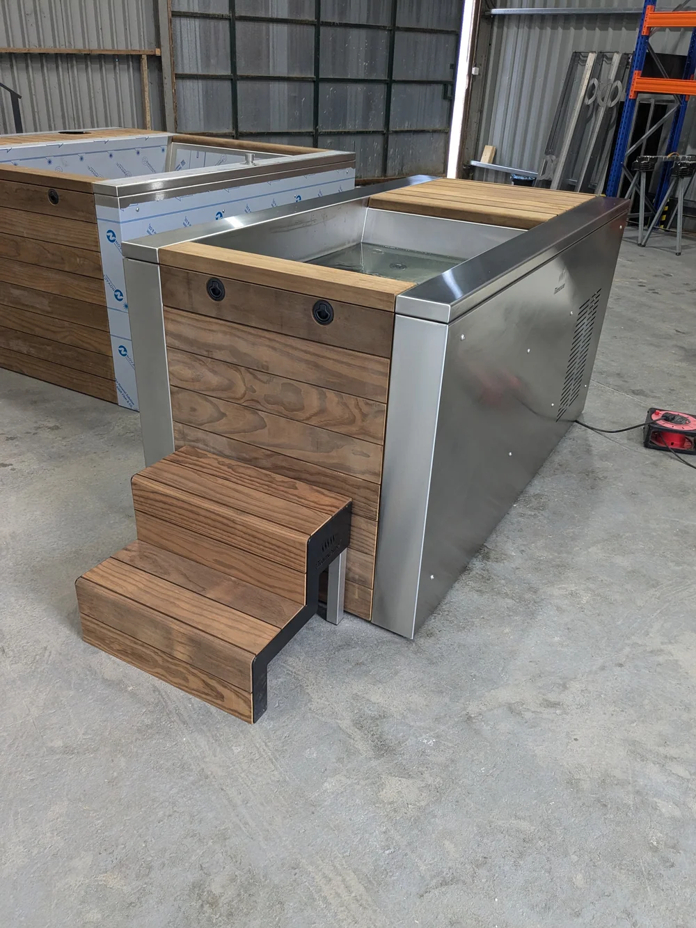 A soaking tub with timber sides and steps, near completion.