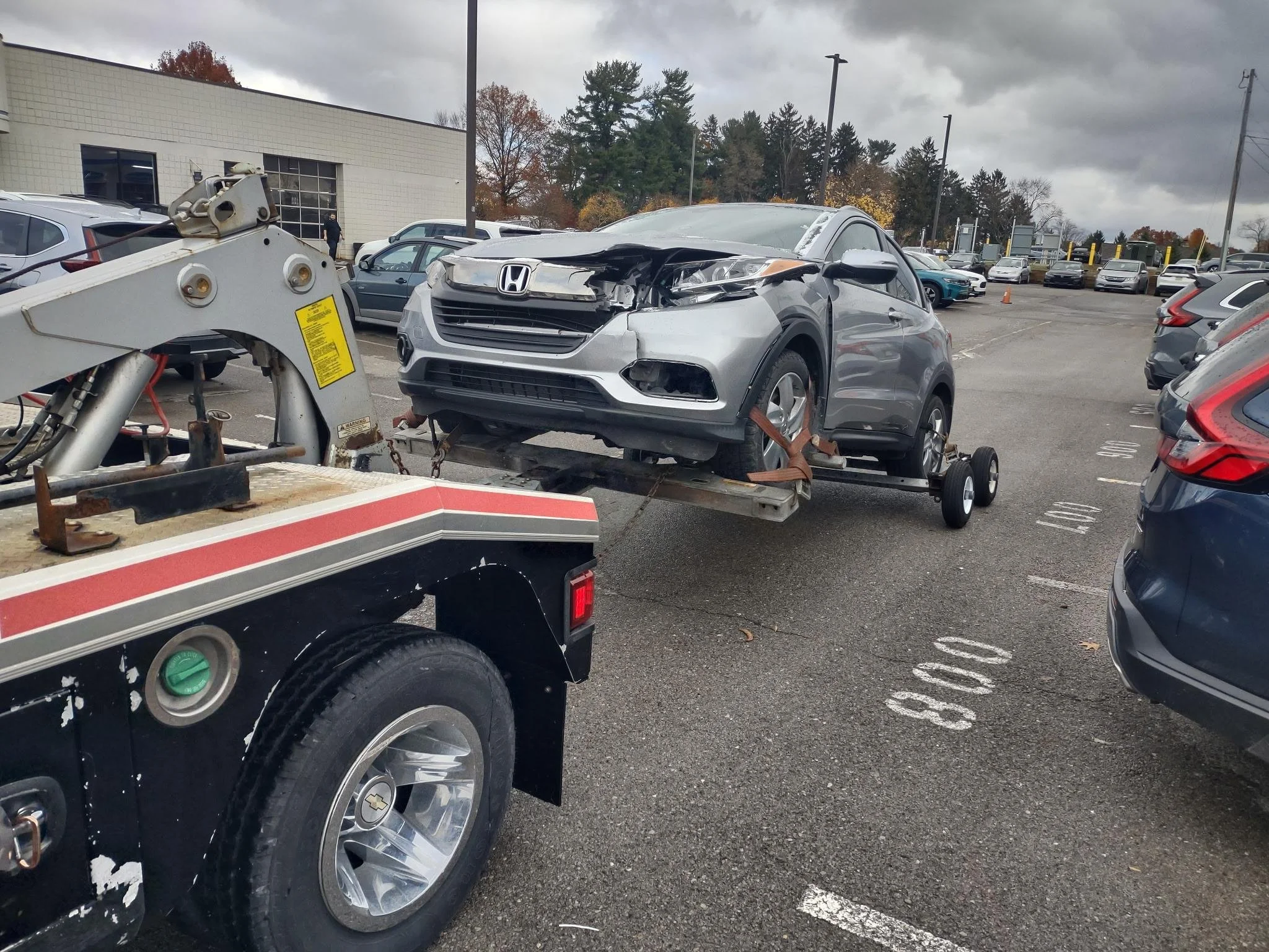 Silver vehicle with front end damage on the back of a tow truck after hitting a deer