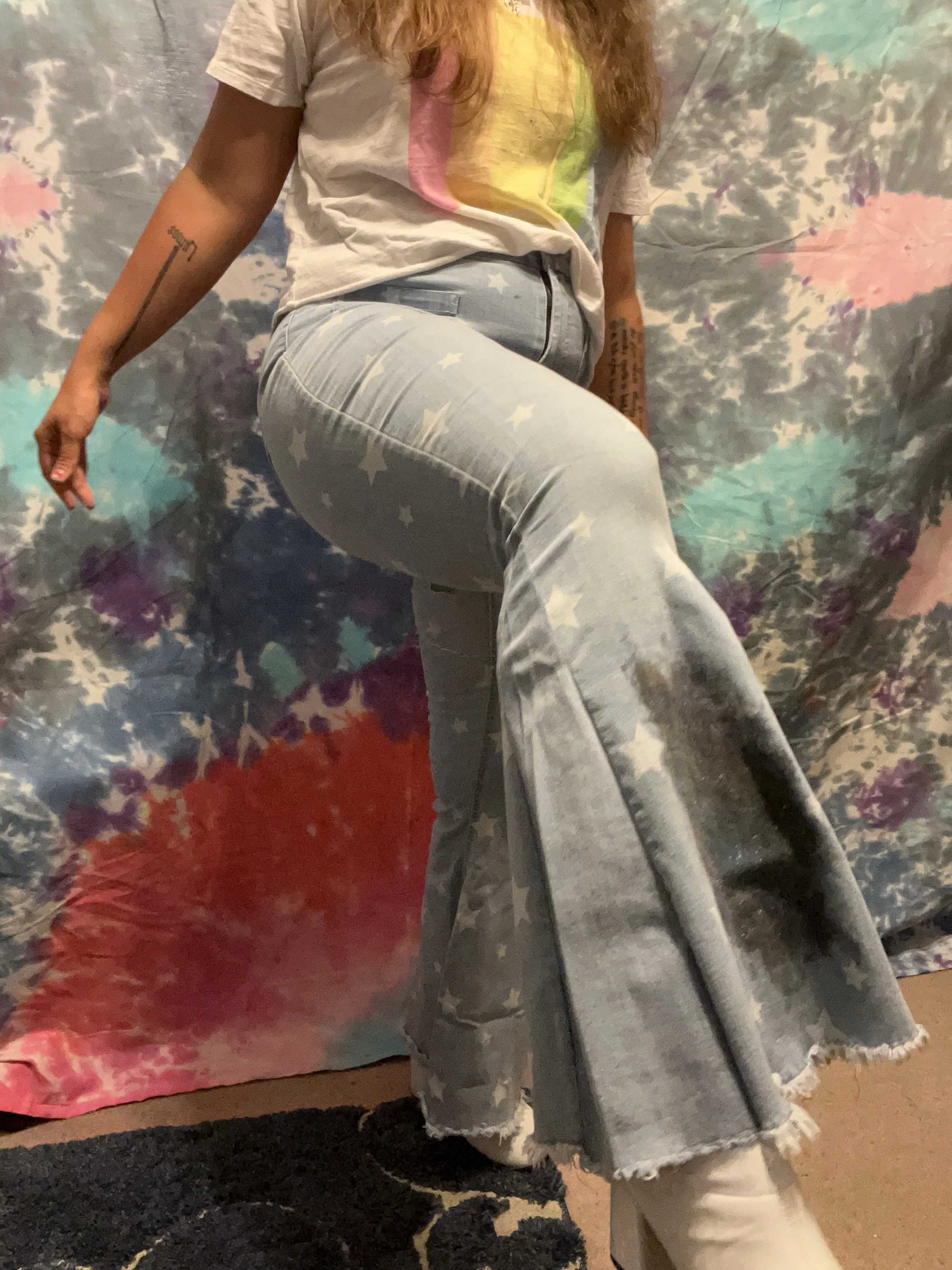 Star printed denim bell-bottoms with light wash denim flare detail, star reverse-applique detail on left upper leg and galaxy paint splotch on the right lower leg