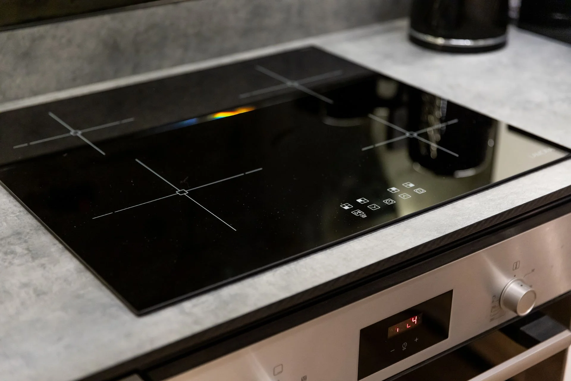 Electric stovetop with four burners and a digital control panel on a kitchen countertop.