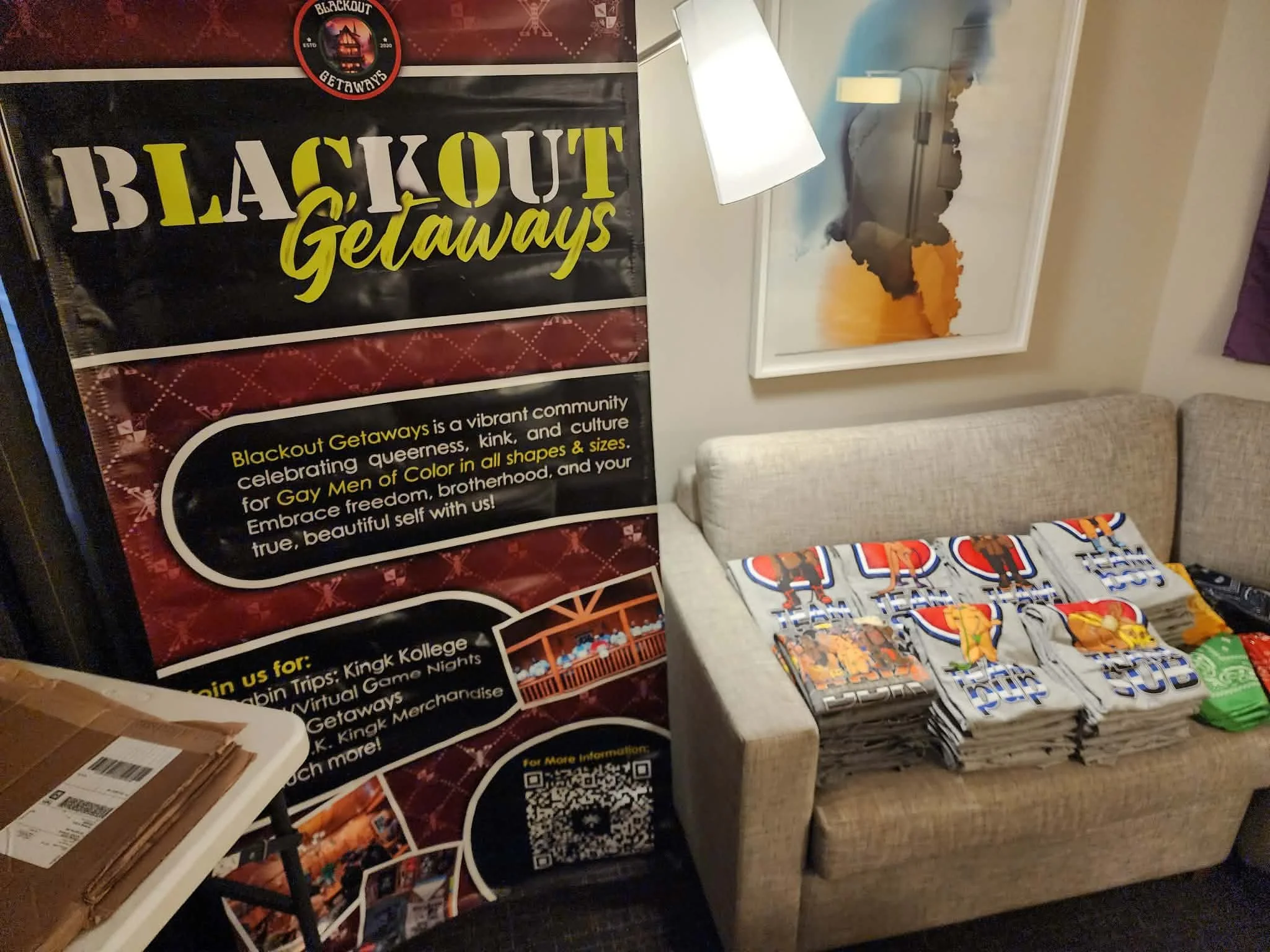 A display table with various wrapped candies and promotional materials for Blackout Getaways, featuring a black and yellow banner and a white lamp.