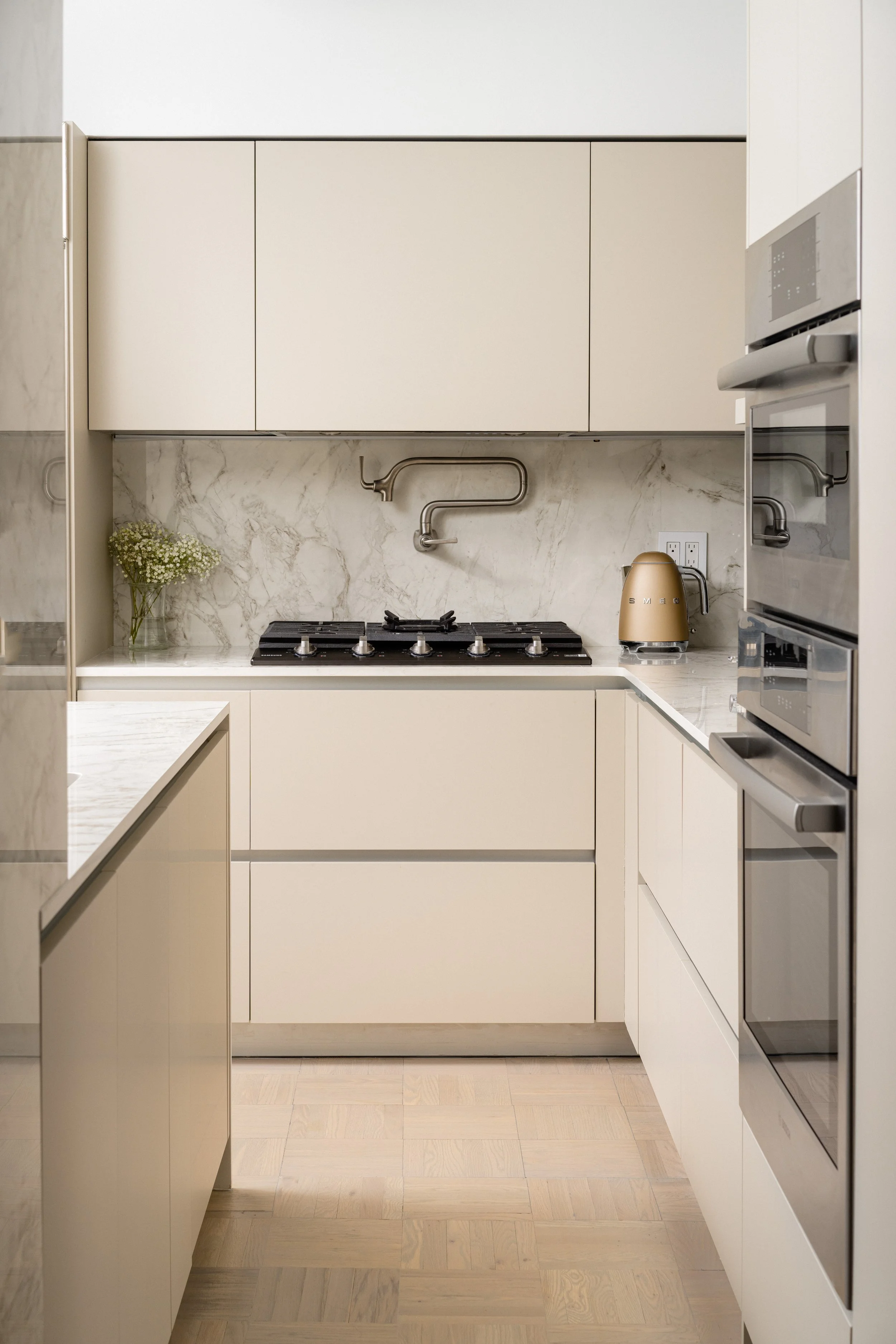 Modern kitchen with white cabinets, marble backsplash, gas stove, toaster, and built-in oven. Kitchen & Bath renovation