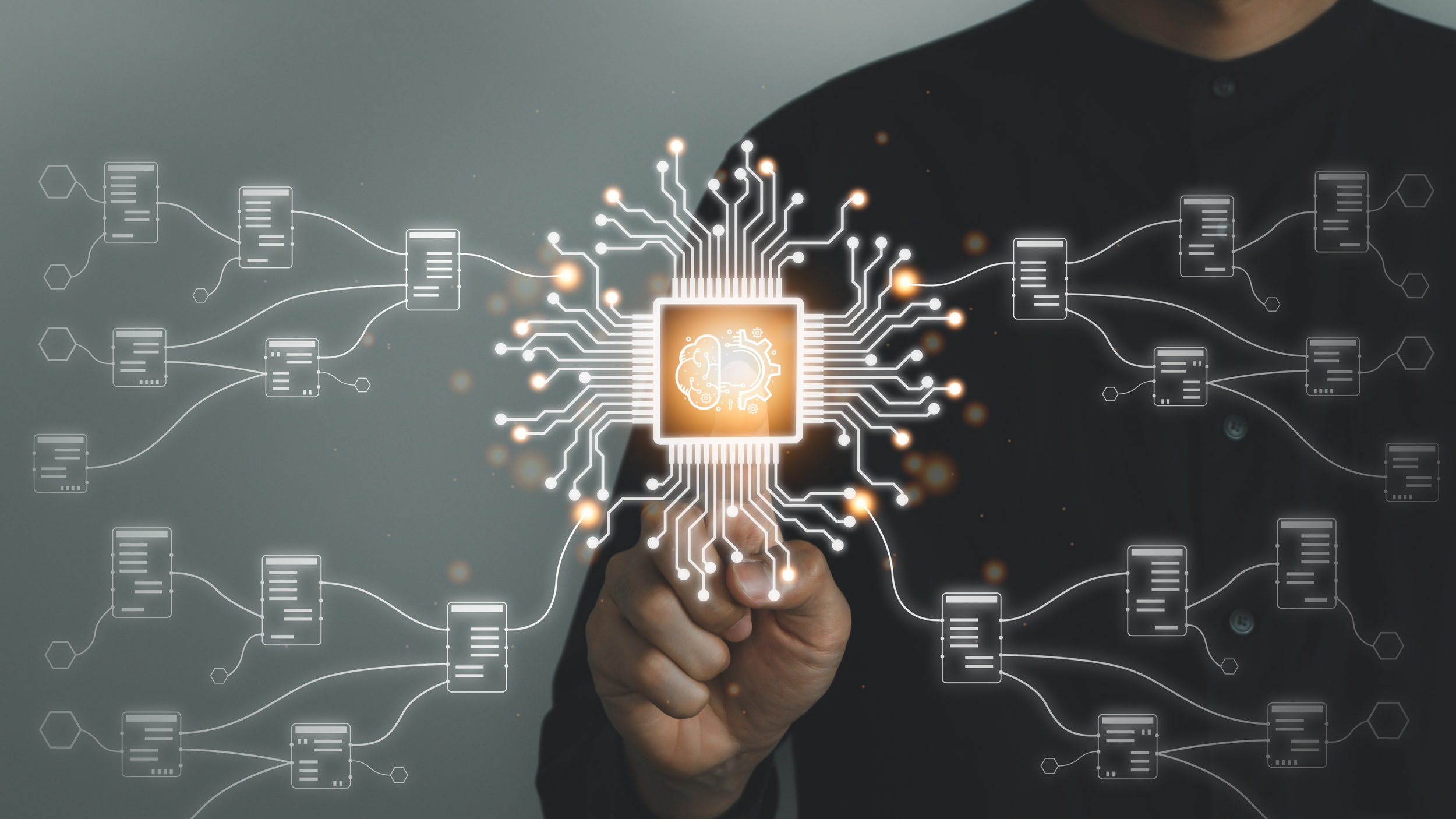 Person in dark shirt points at a digital illustration of a microchip with neural network and circuit connections, with a brain icon in the center, glowing effects around it.