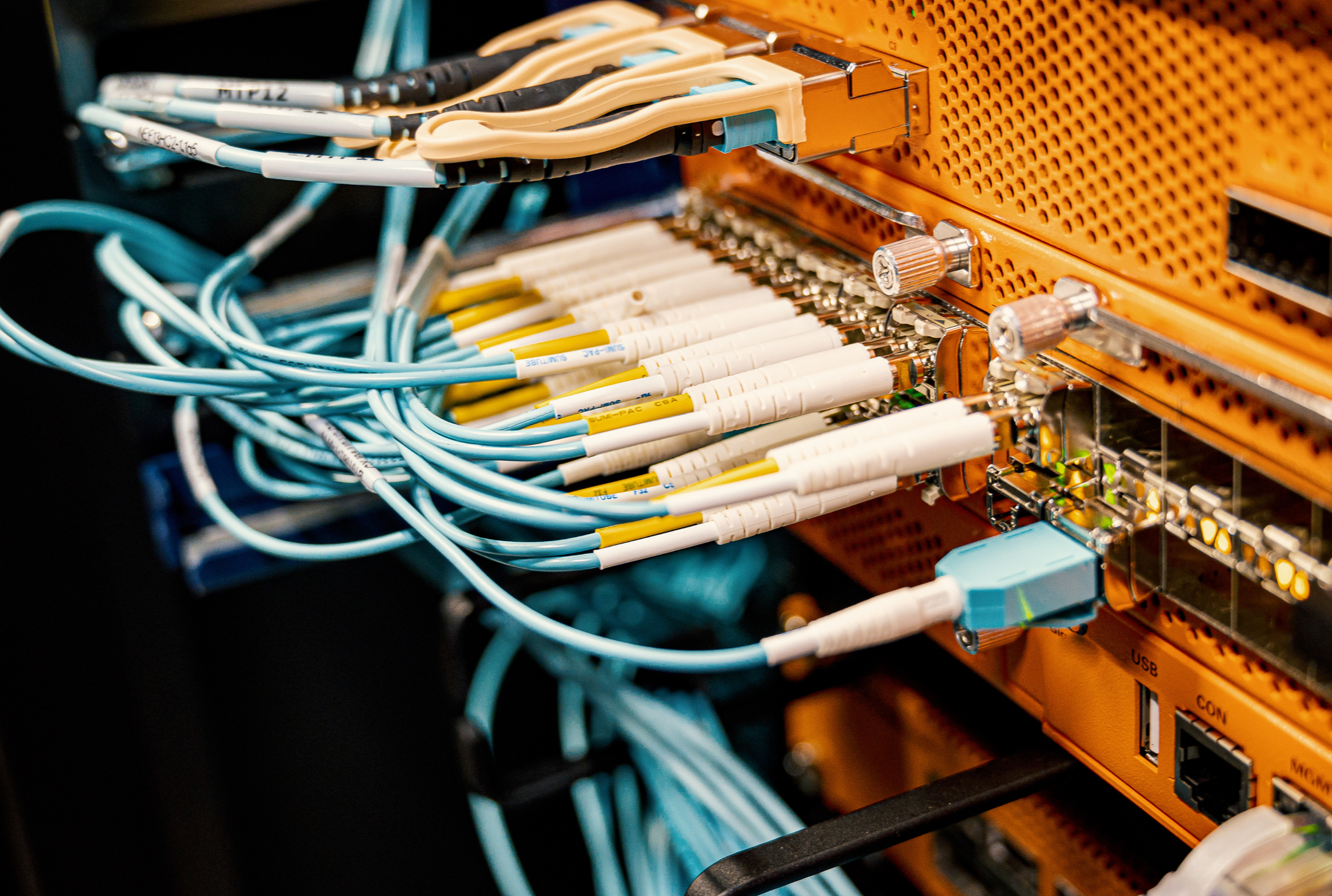 Close-up view of network cables and connectors attached to a telecommunications or server hardware with orange metallic panels.