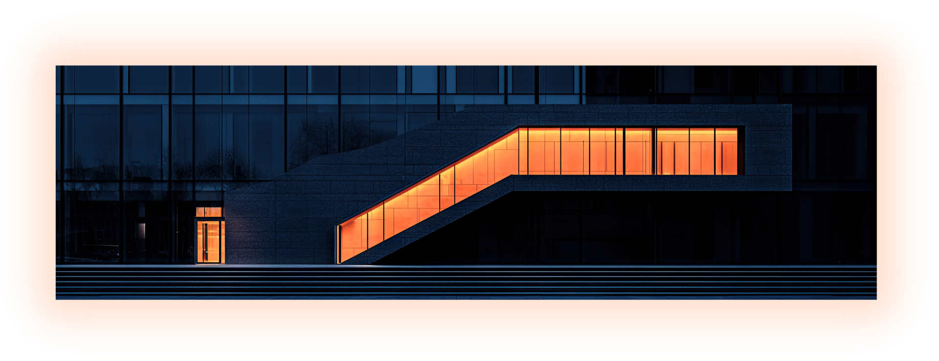 Modern building with glass facade and illuminated orange staircase at night.