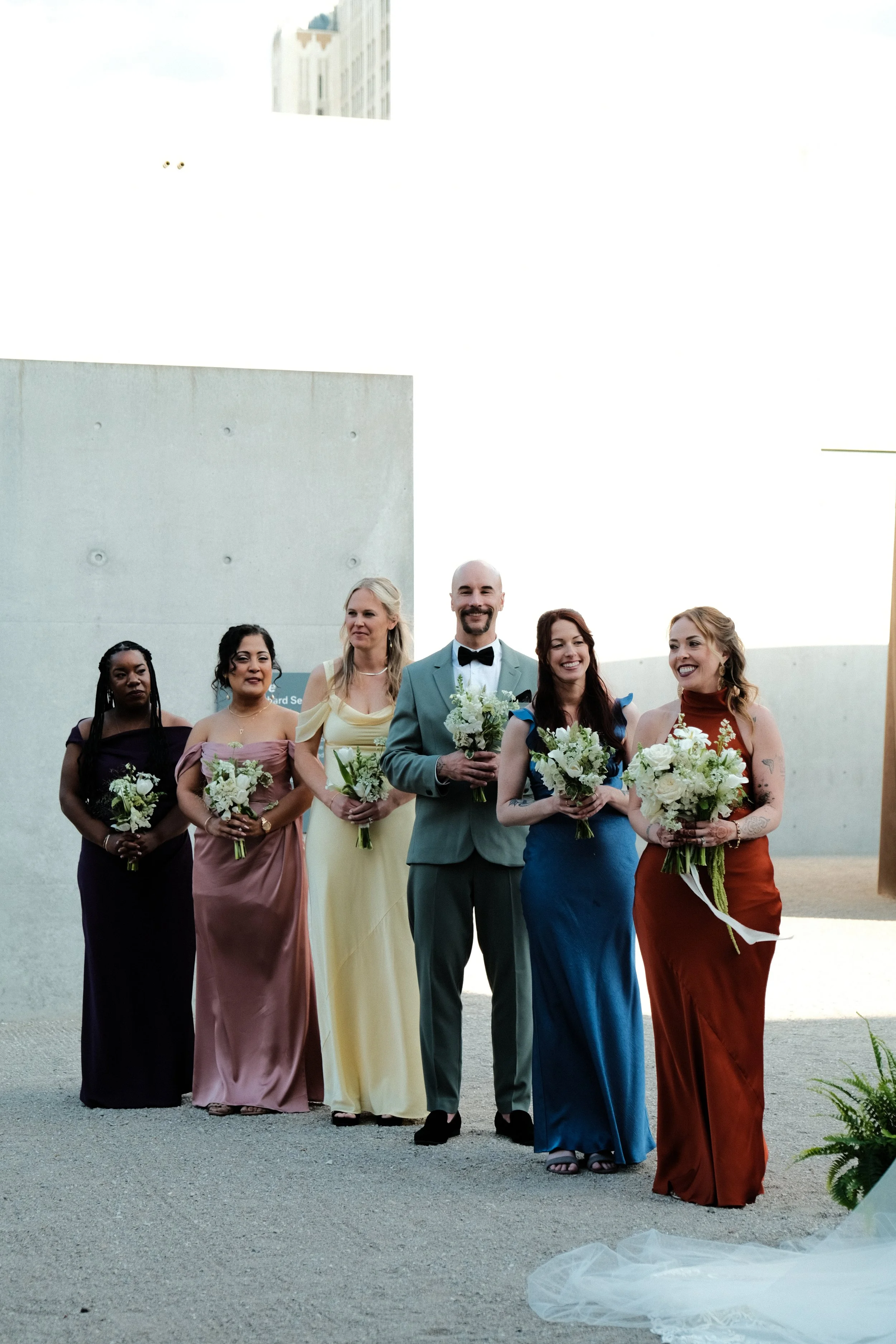 A group of six wedding party attendants standing in a row holding bouquets designed by St. Louis florist, Suncrest Blooms.