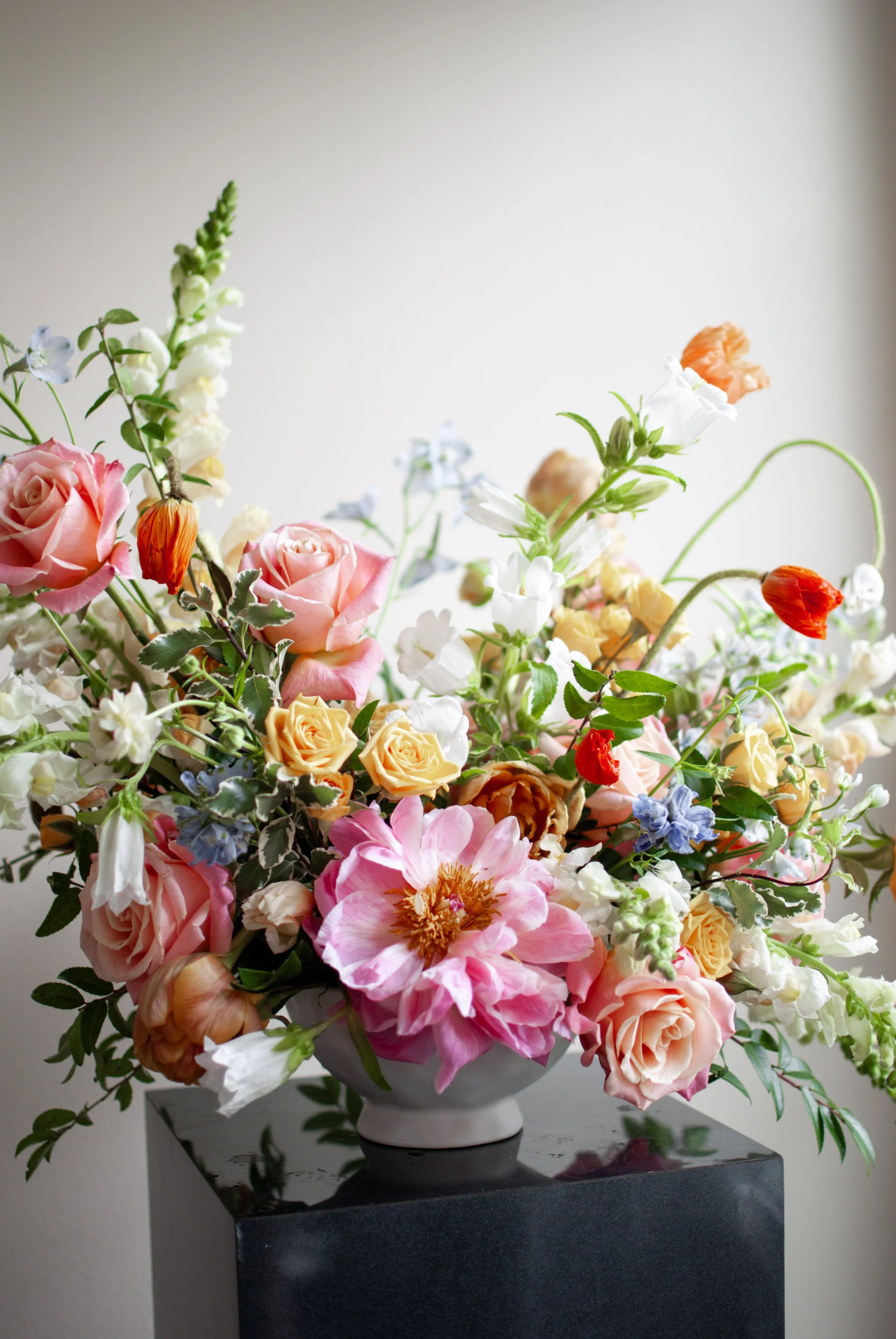 Colorful flower arrangement with flowers in shades of pink, yellow, white, peach, blue and greenery. Designed by St. Louis Florist, Suncrest Blooms.