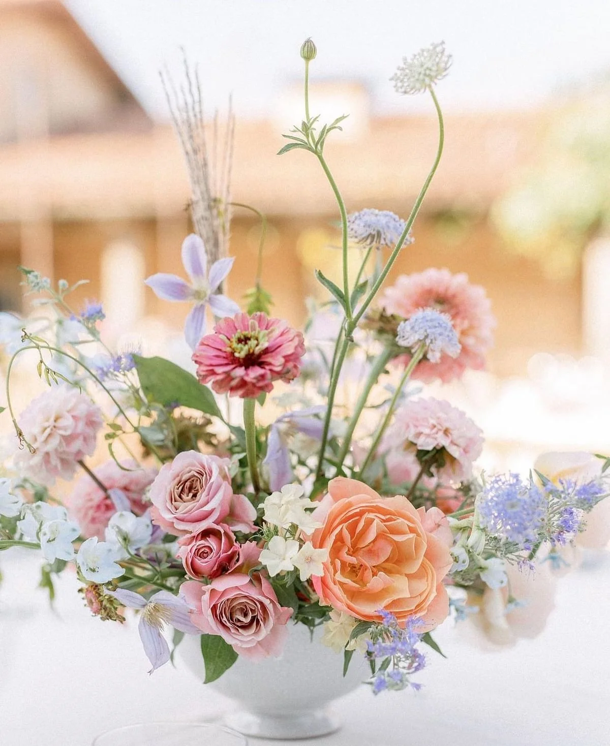 A bouquet of mixed pastel-colored flowers in a white vase, including roses, peonies, and other blossoms. St. Louis Wedding Florist, Suncrest Blooms.