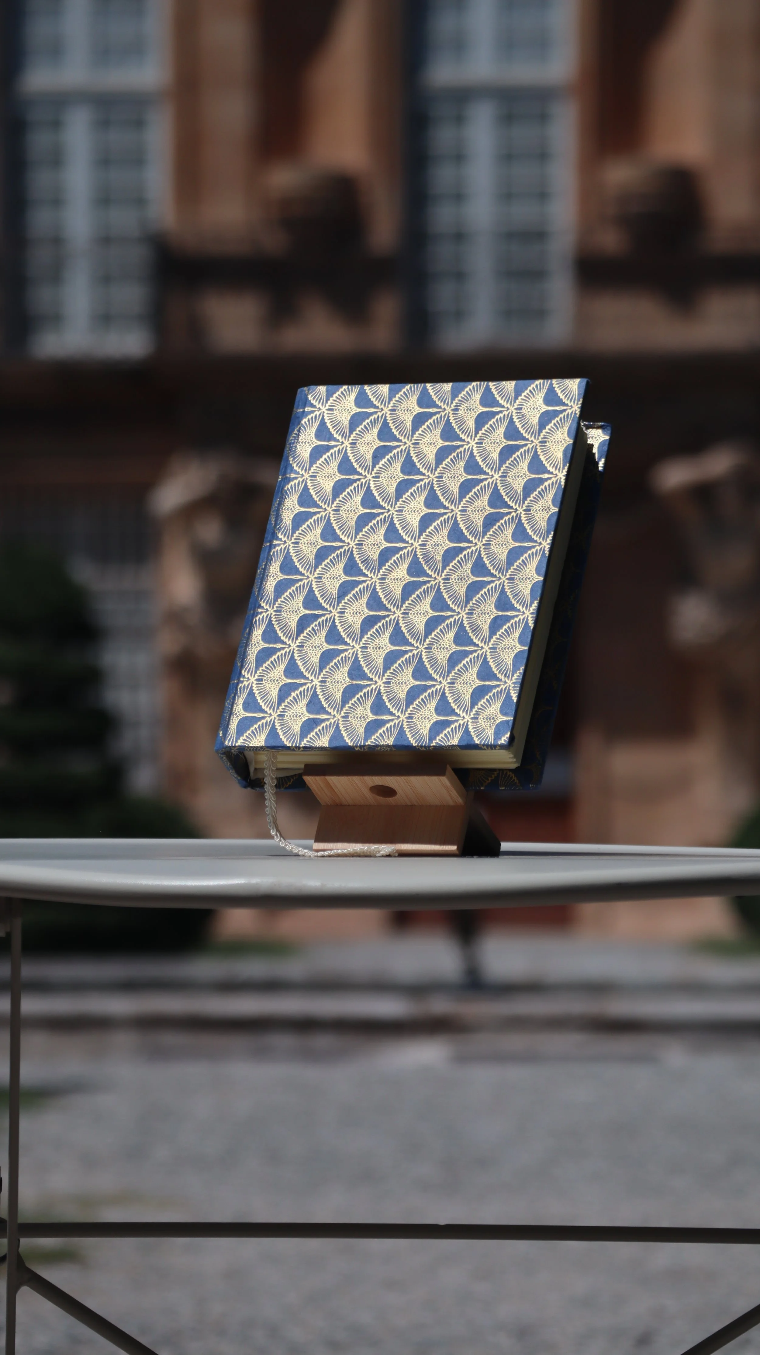 Un livre avec une couverture bleue et un motif blanc, posé sur un support en bois