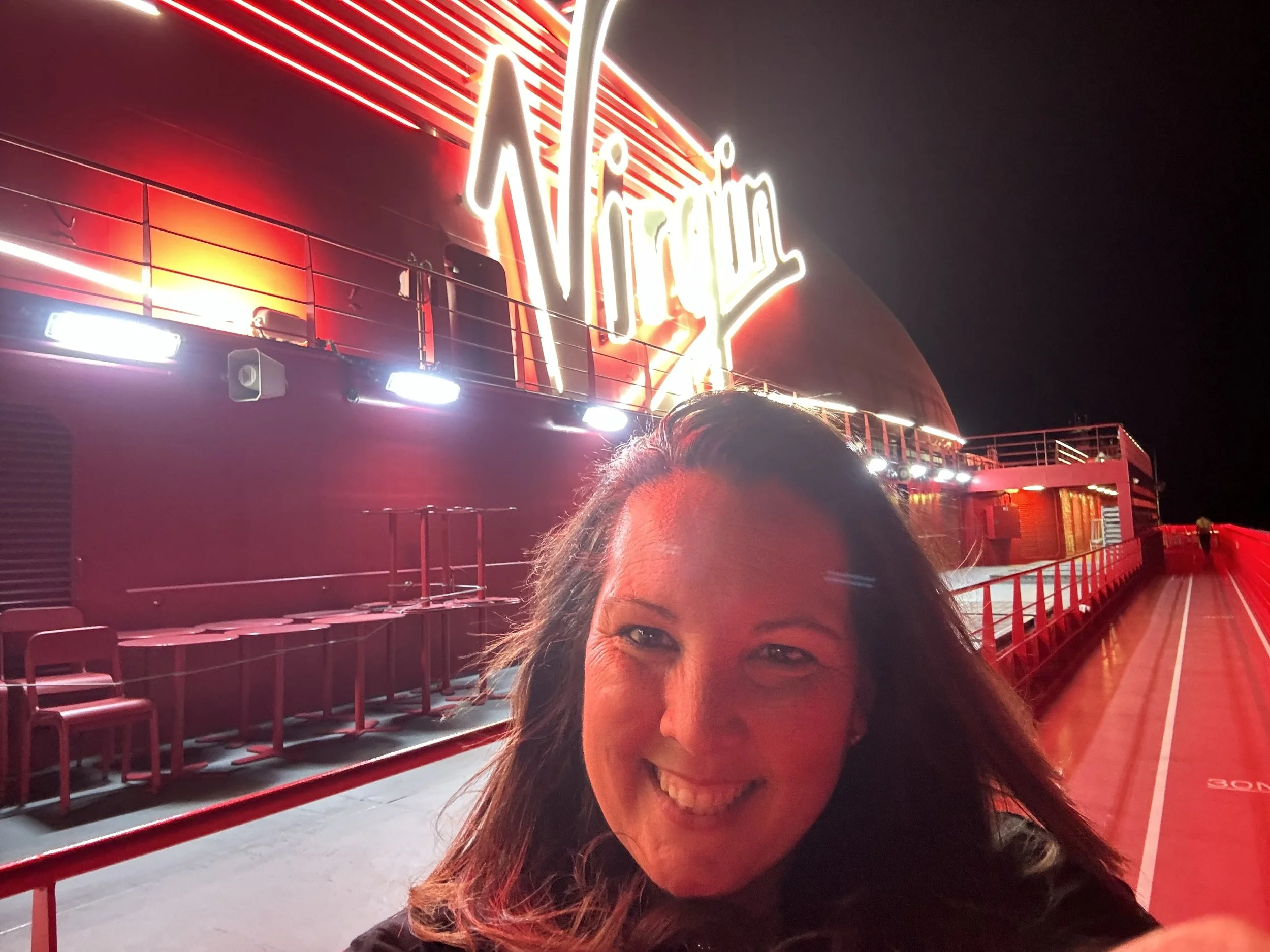 Smiling woman taking selfie at a night scene outside a neon-lit stadium with a large illuminated sign reading 'Vikings' in the background.