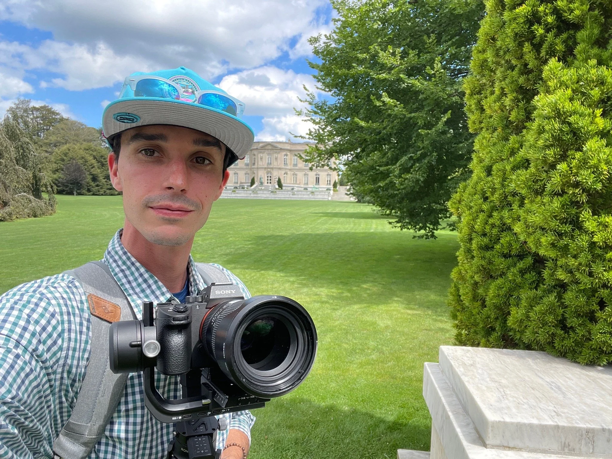 Wedding photographer holding a camera in the gardens at The Elms in Newport, Rhode Island.