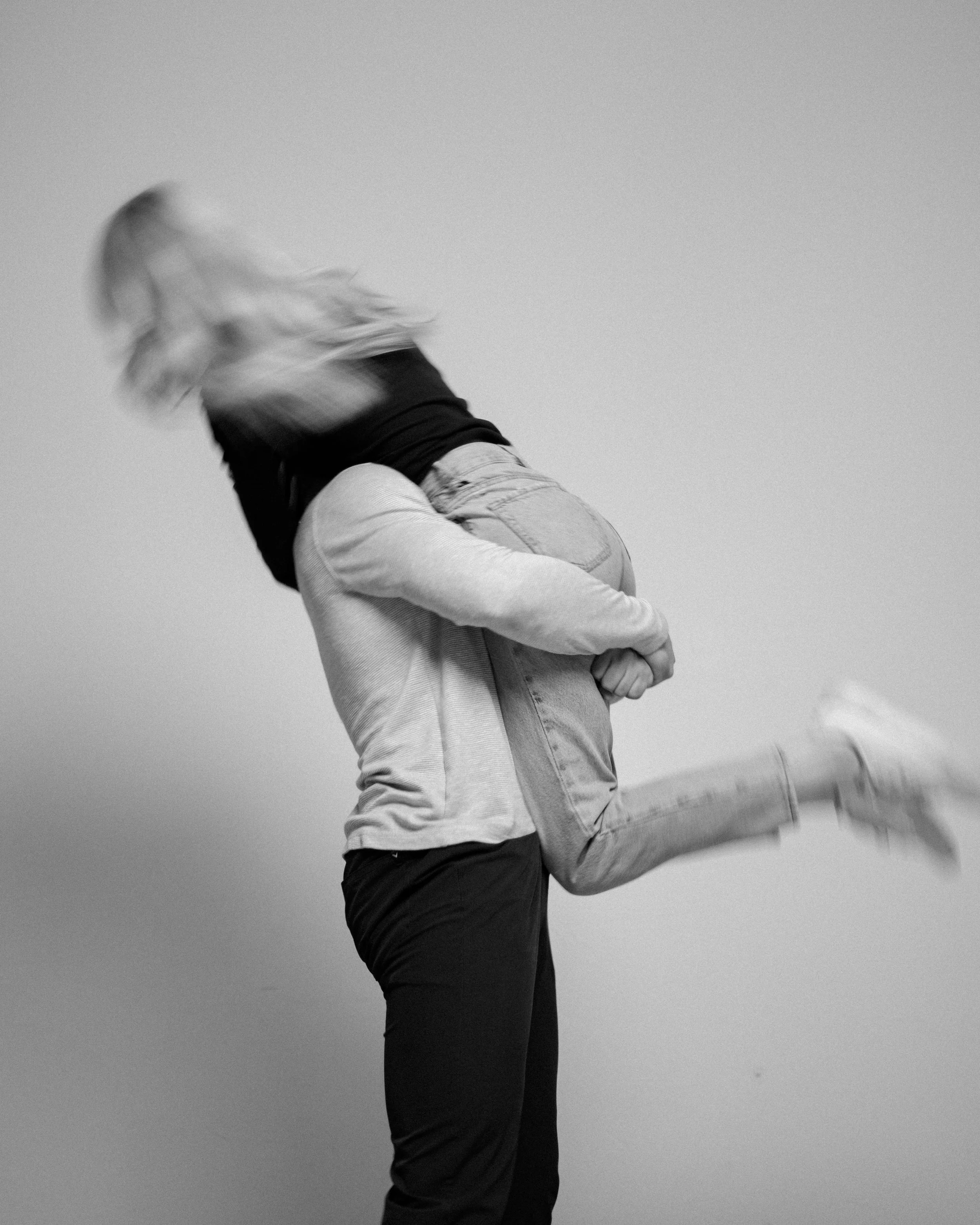 A person giving another person a piggyback ride, blurred motion, in black and white.