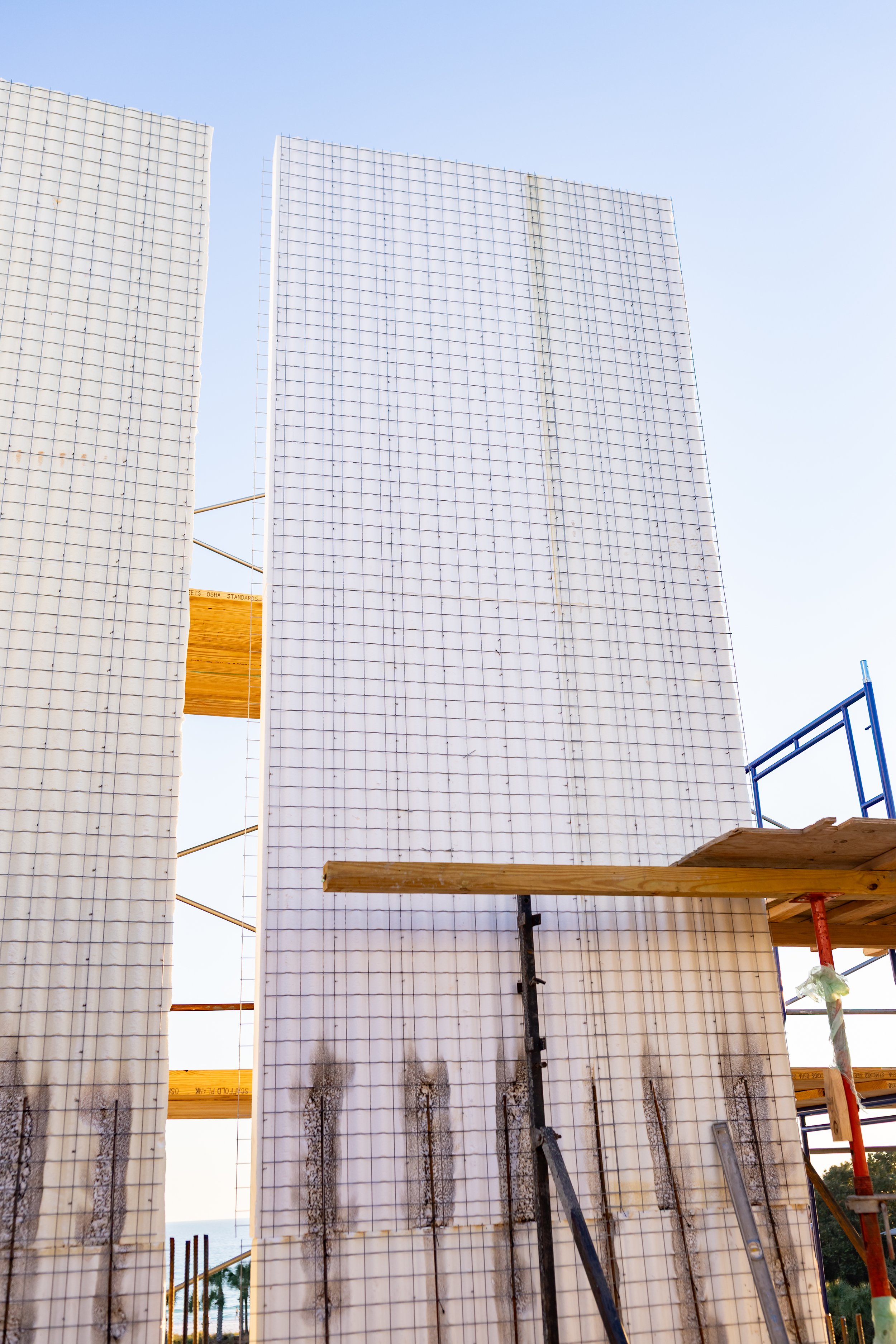 Construction site with concrete forms and scaffolding, with a clear sky in the background.