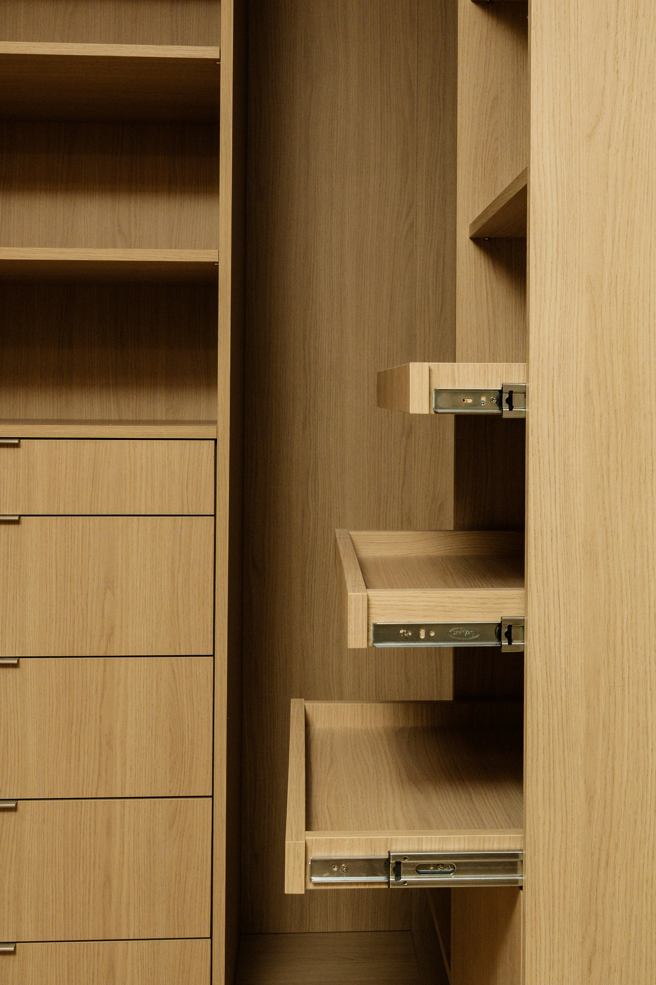 Open empty drawers in a light wood cabinet.