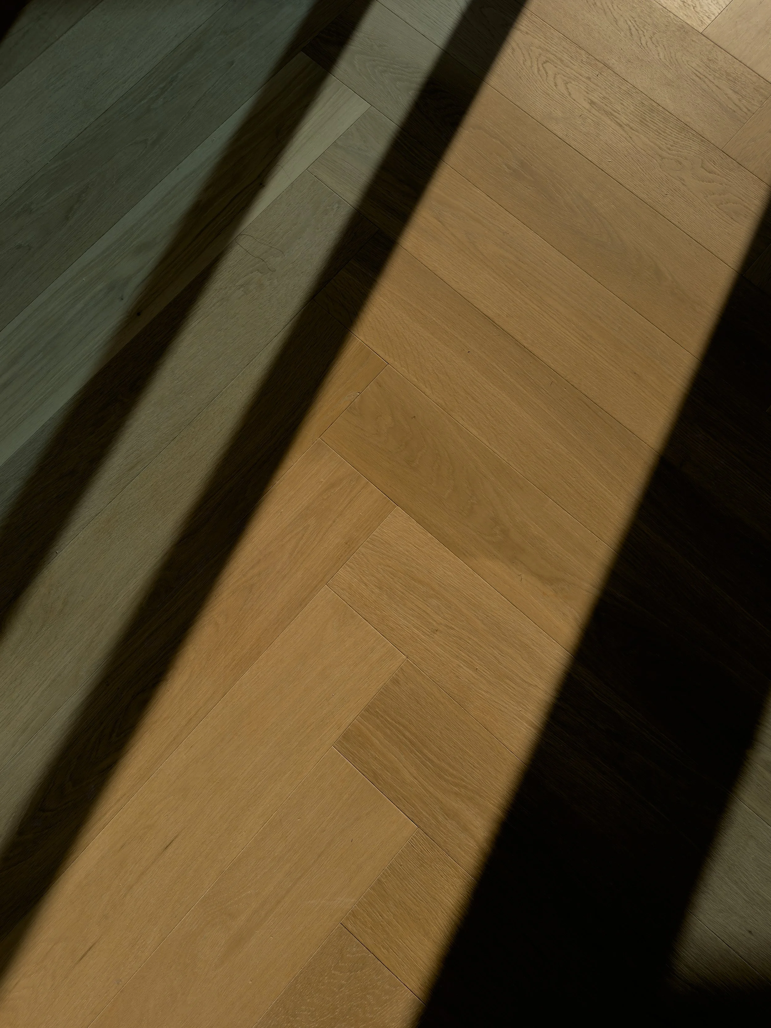 Wooden floor with shadows cast by window blinds.