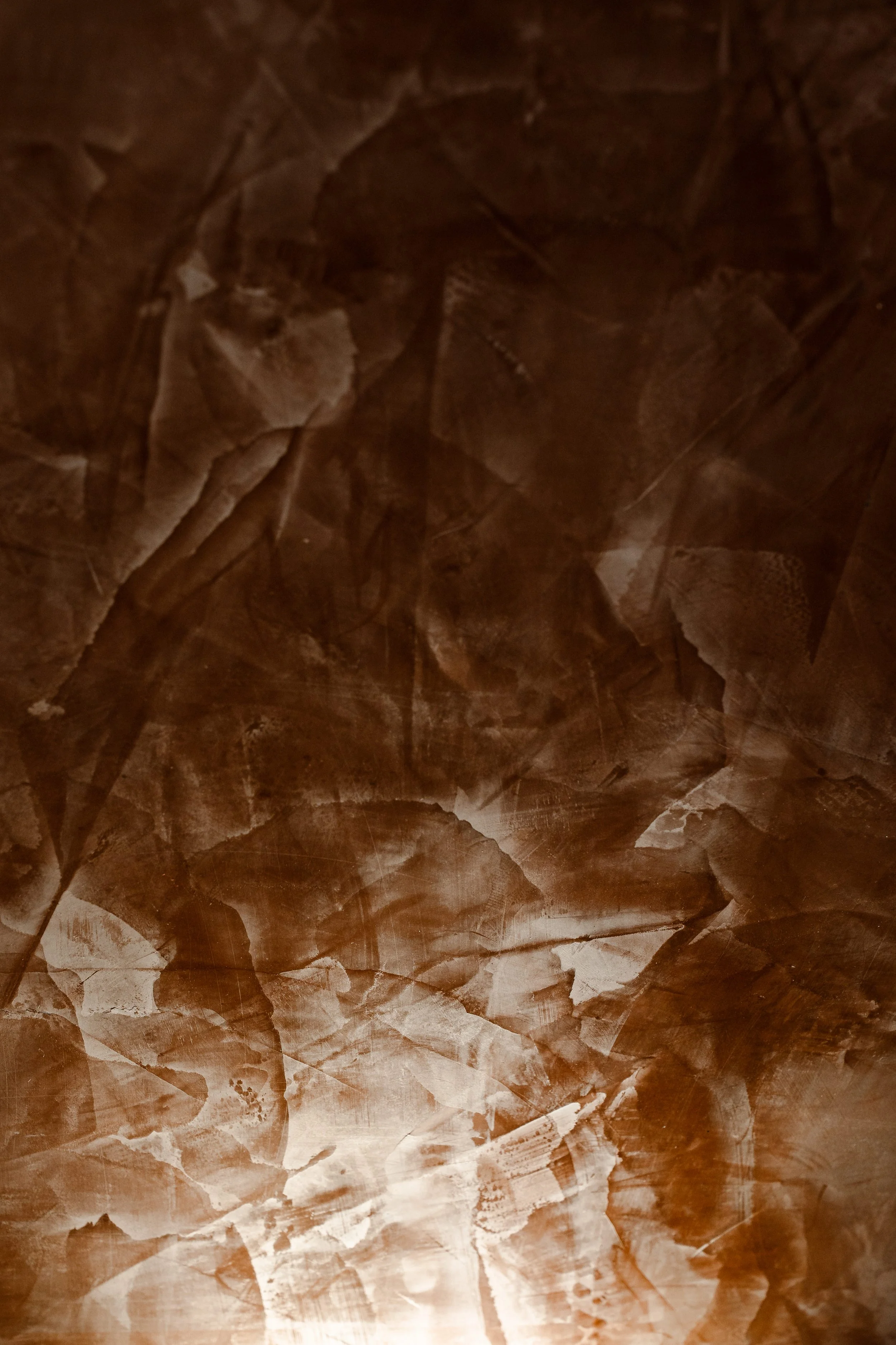 Close-up of a textured surface resembling crumpled or scratched metal with a dark brown and copper color palette.