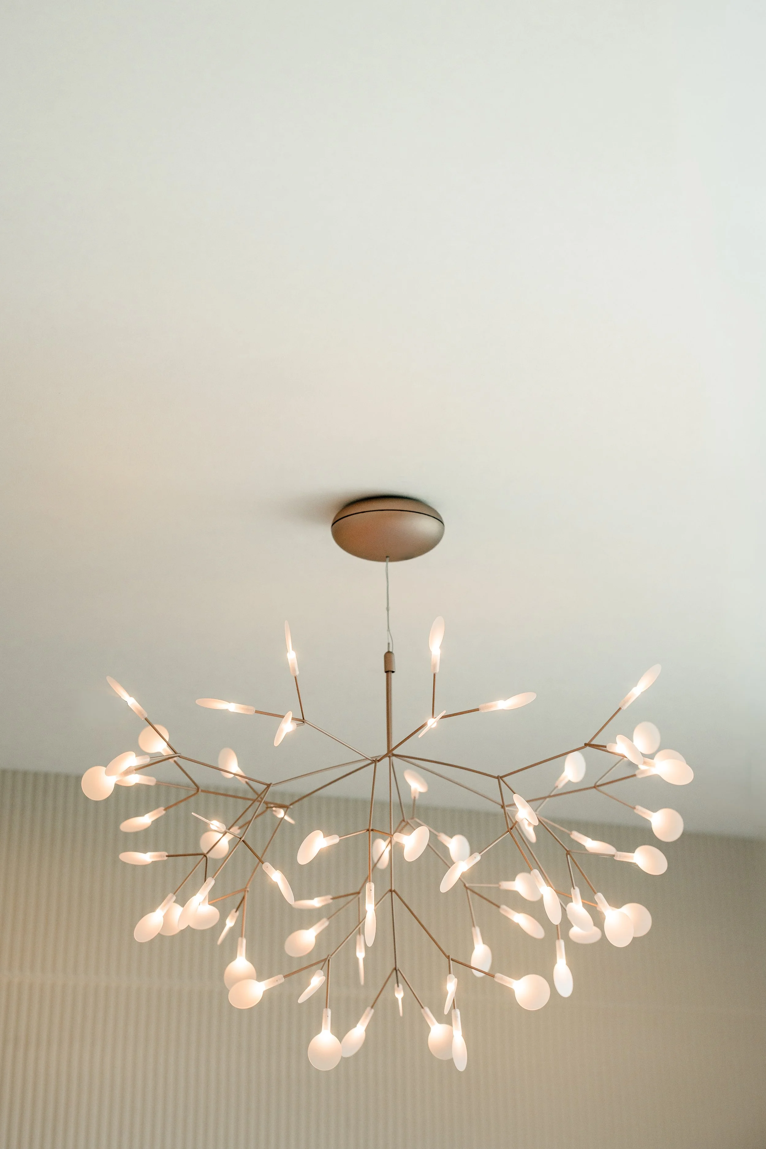 Modern chandelier with multiple light bulbs hanging from a ceiling.