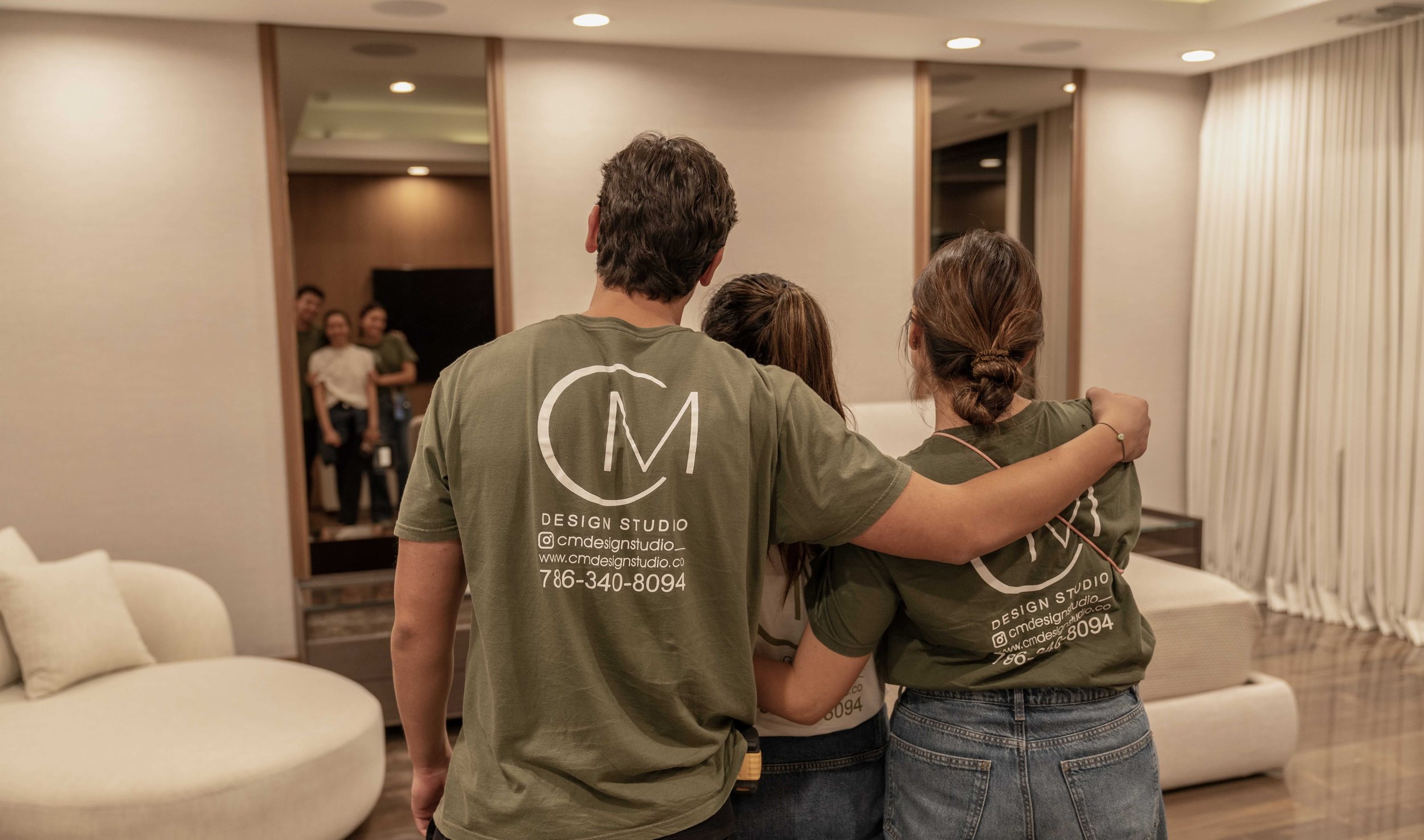 Casa Medina team standing together in a finished living room, reflected in the mirror of a Miami home.