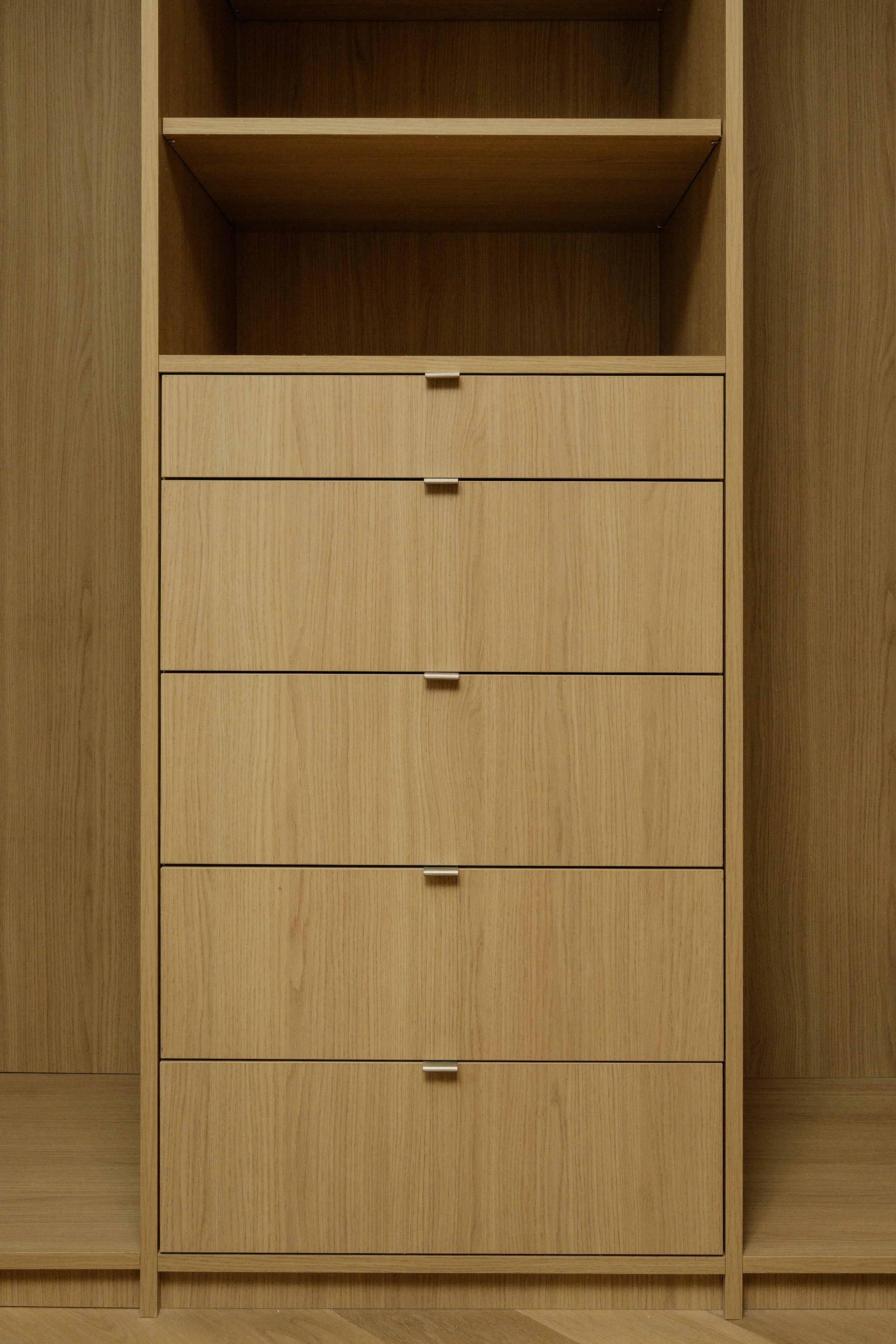 A wooden cabinet with six drawers and open shelves above, made of light-colored wood with a visible grain pattern.