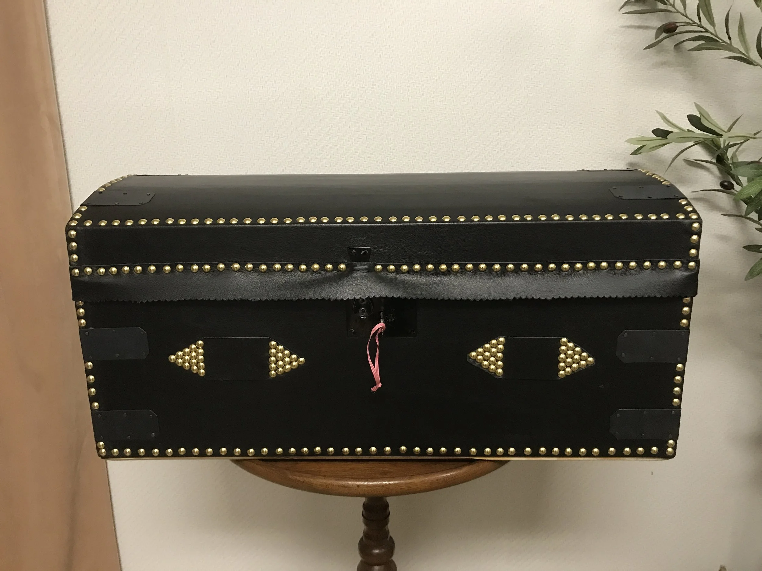 A leather covered trunk in a size convenient for travel, with reinforced corners and rope holders.