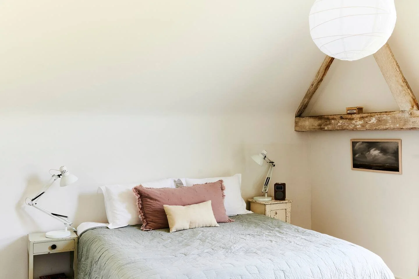 A bedroom with a white bed, pink and cream pillows, two white bedside lamps, hawthbush farm weddings east sussex group cottages
