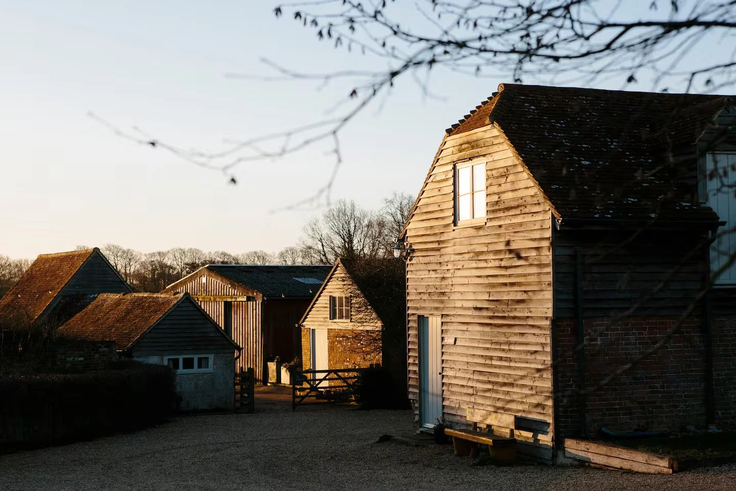 A rural farm scene during sunset featuring several old wooden and brick farm buildings, Sussex Group Booking.