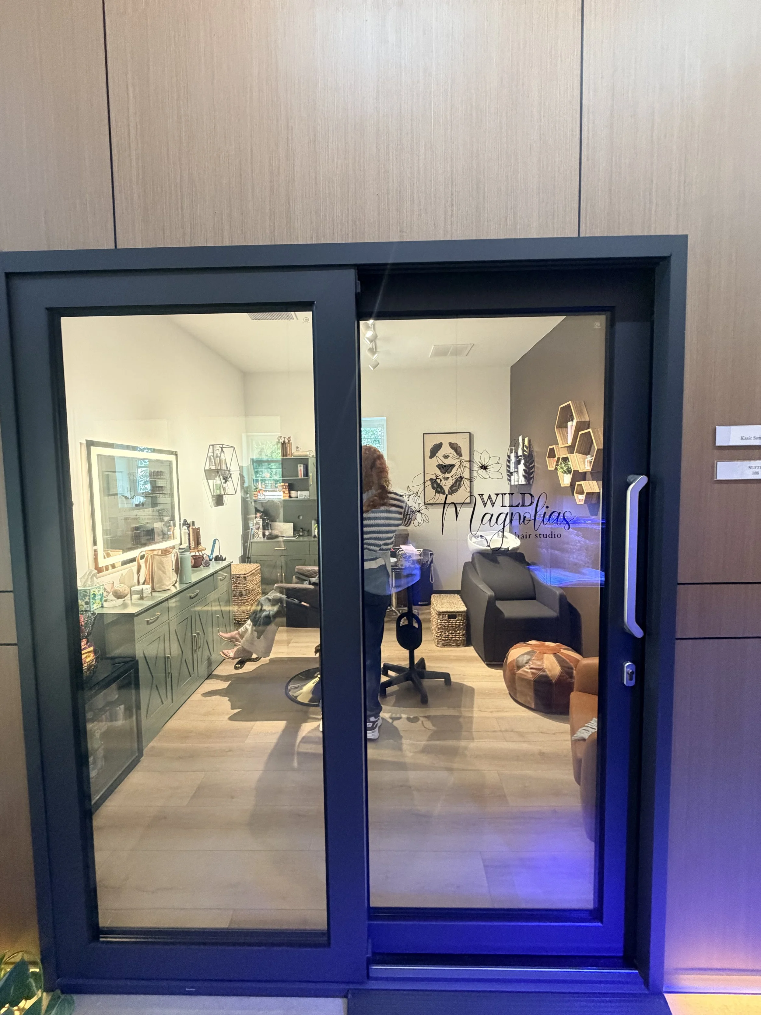 Salon with two oval mirrors, hair styling chairs, and a neon sign on the wall that says "You're like, really pretty."