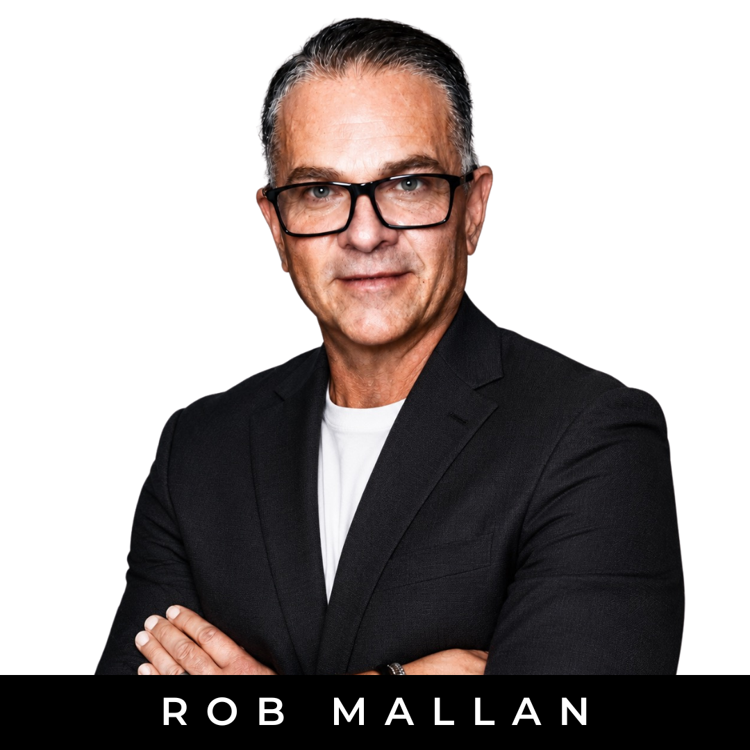 A middle-aged man with gray hair, wearing glasses, a dark checkered blazer, and a yellow shirt, standing with arms crossed against a white background with a black band at the bottom displaying the text 'Rob Mallan'.