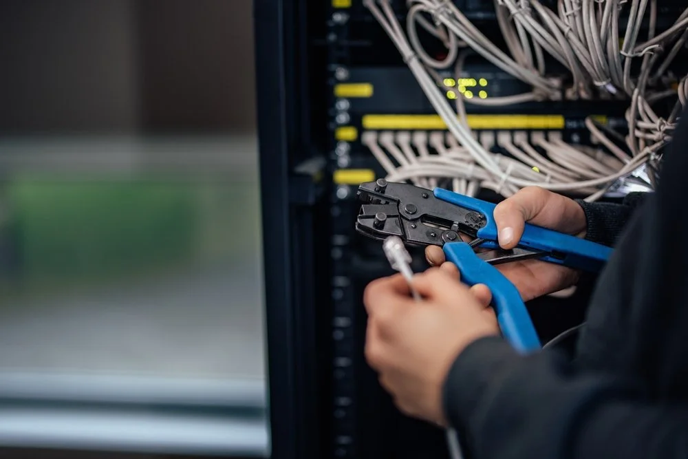 Crimping RJ45 connector, close-up. Man holding hand crimping tool and ethernet cable.