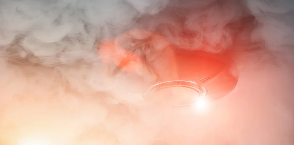 Close up of smoke detector alarm ringing while surrounded by smoke