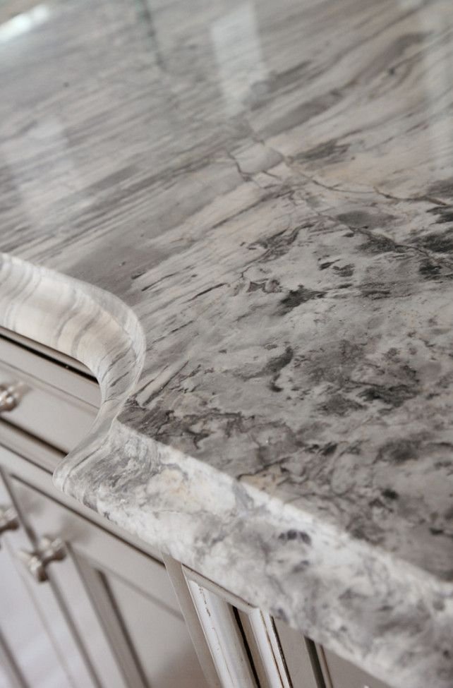 Close-up of a gray and white marble kitchen countertop with a rounded edge.