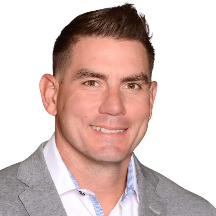 Headshot of a smiling man in a gray suit and white shirt against a plain background.