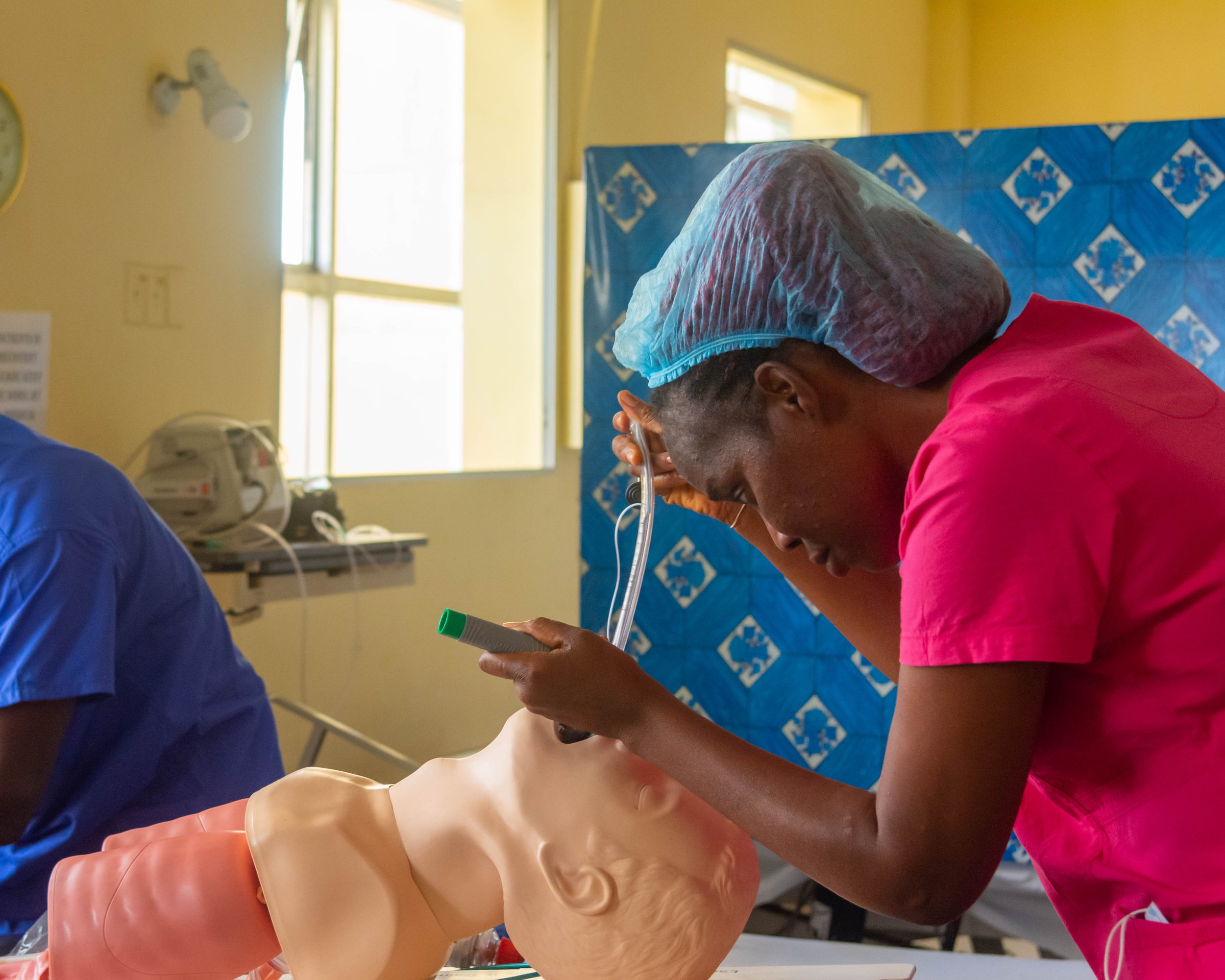 Two surgeons wearing scrubs, masks, gloves, and surgical caps performing a procedure in an operating room.