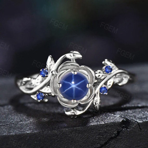 Silver ring with a large blue gemstone center surrounded by smaller blue stones on a dark surface.