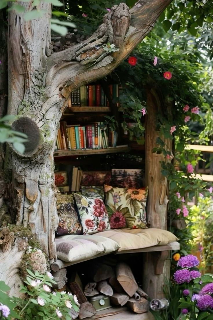Cozy window seat with colorful embroidered cushions, surrounded by plants and bookshelves, in a sunlit room with white curtains and a large window showing a tree outside.