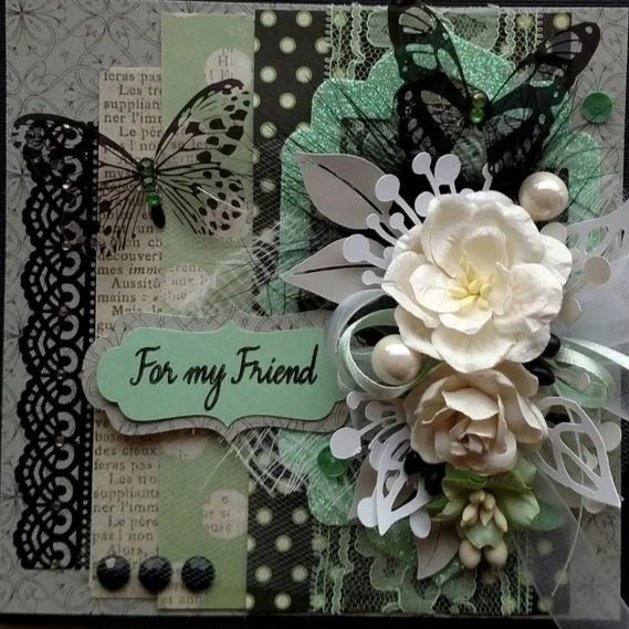 Decorative greeting card with black butterfly cutouts, polka dot and lace patterns, and white flowers with greenery. A light green label reads "For my Friend."