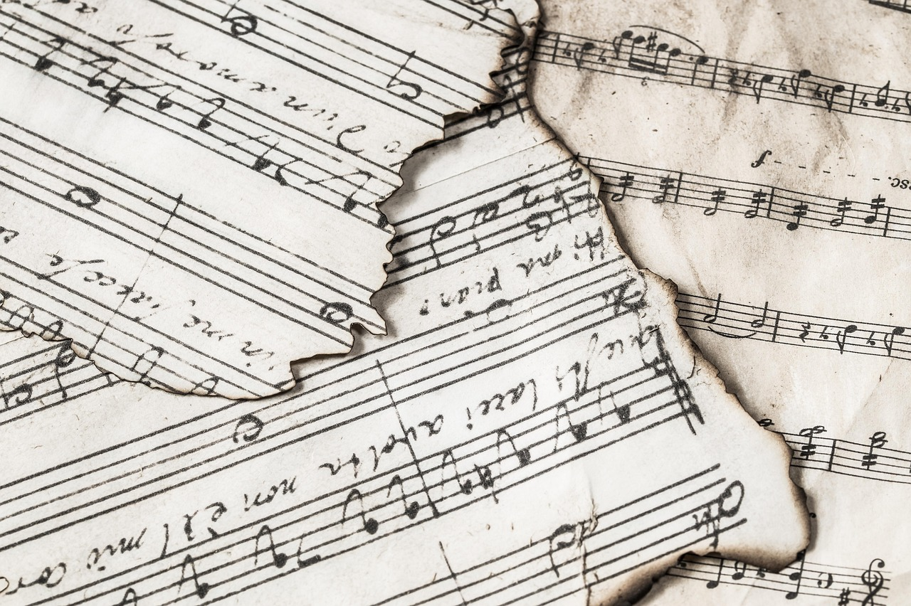 Torn and weathered sheet music with handwritten notes and musical staff lines.