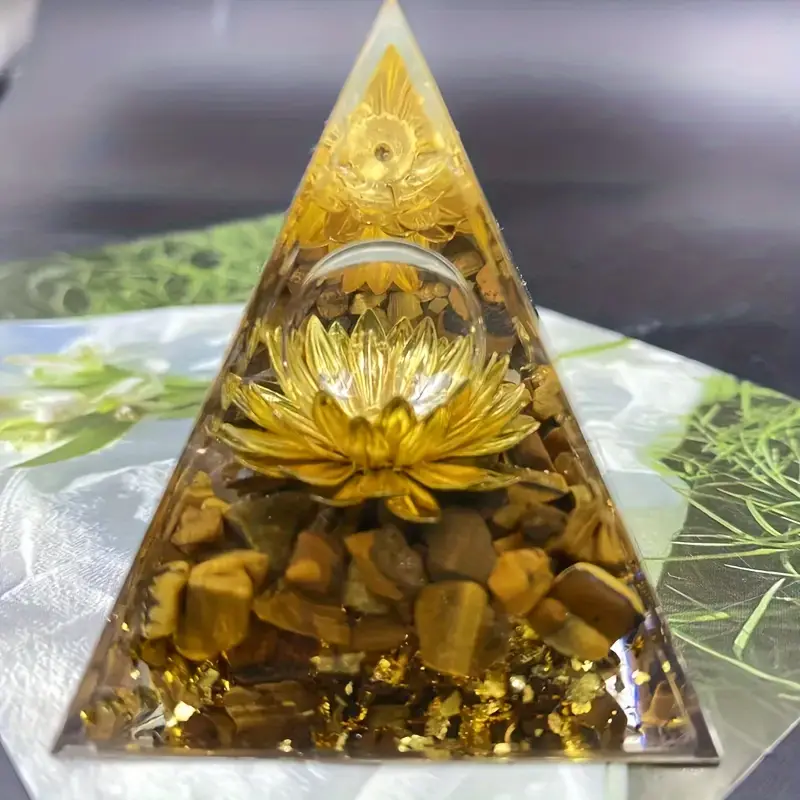 A clear pyramid-shaped resin ornament containing yellow flowers and small stones.