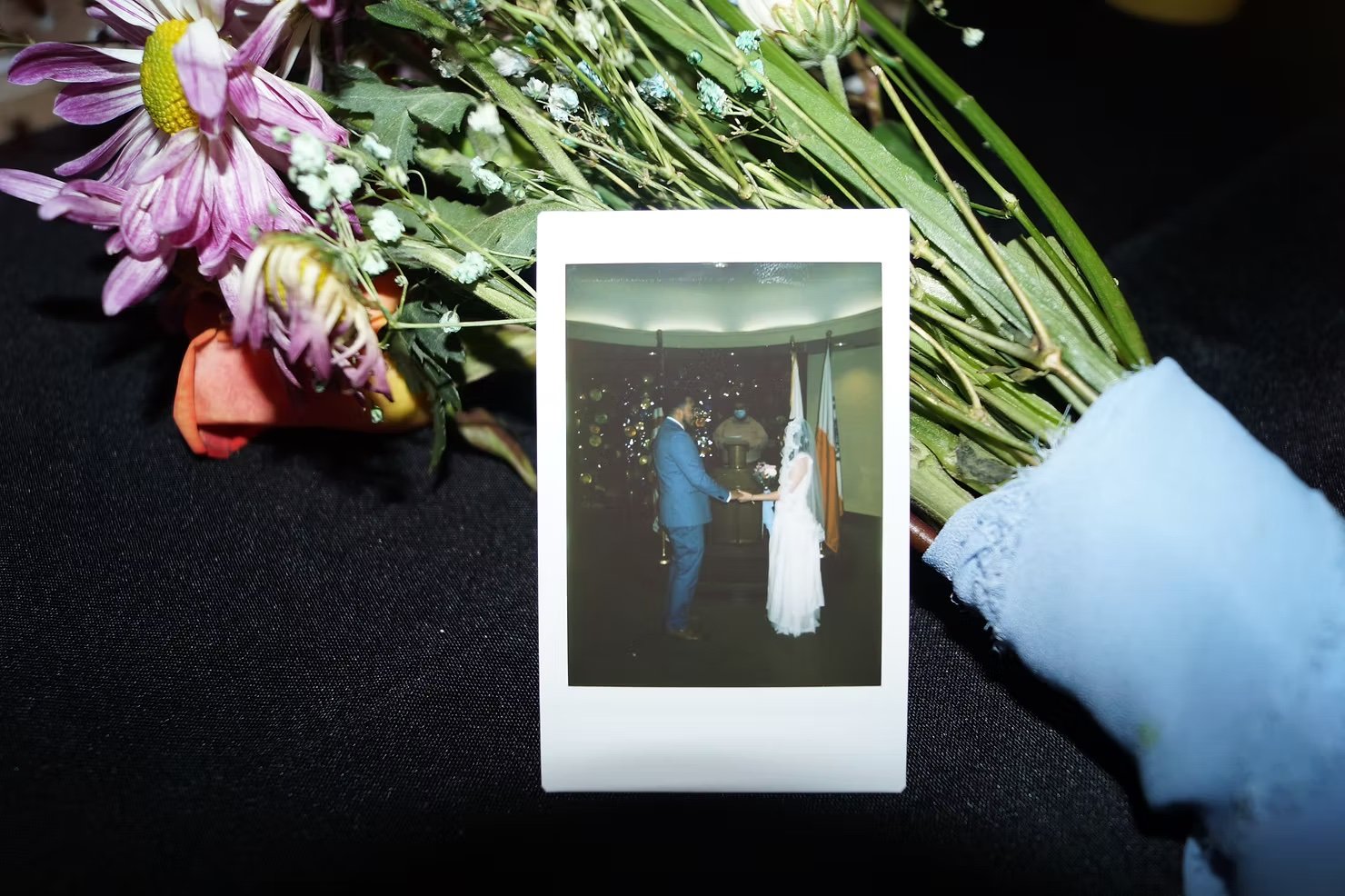 image of a polaroid my husband and I getting married on top of a flower bouquet