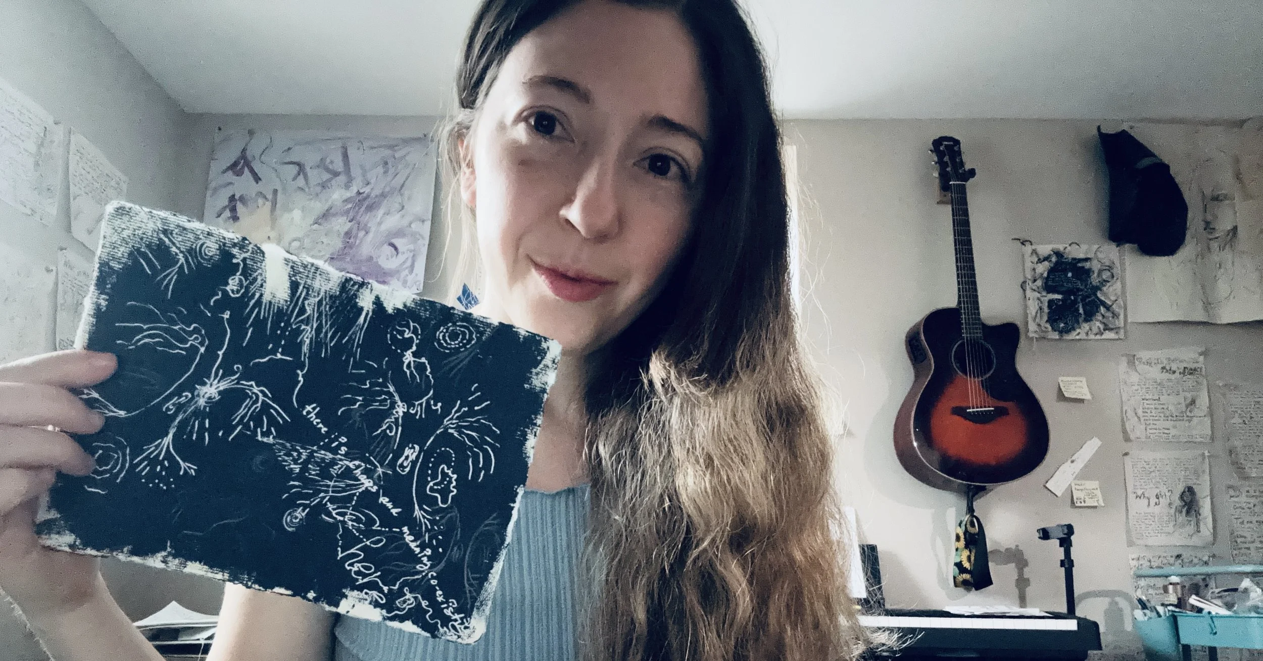 a photo of Nicole Javorsky in her studio holding up a new artwork