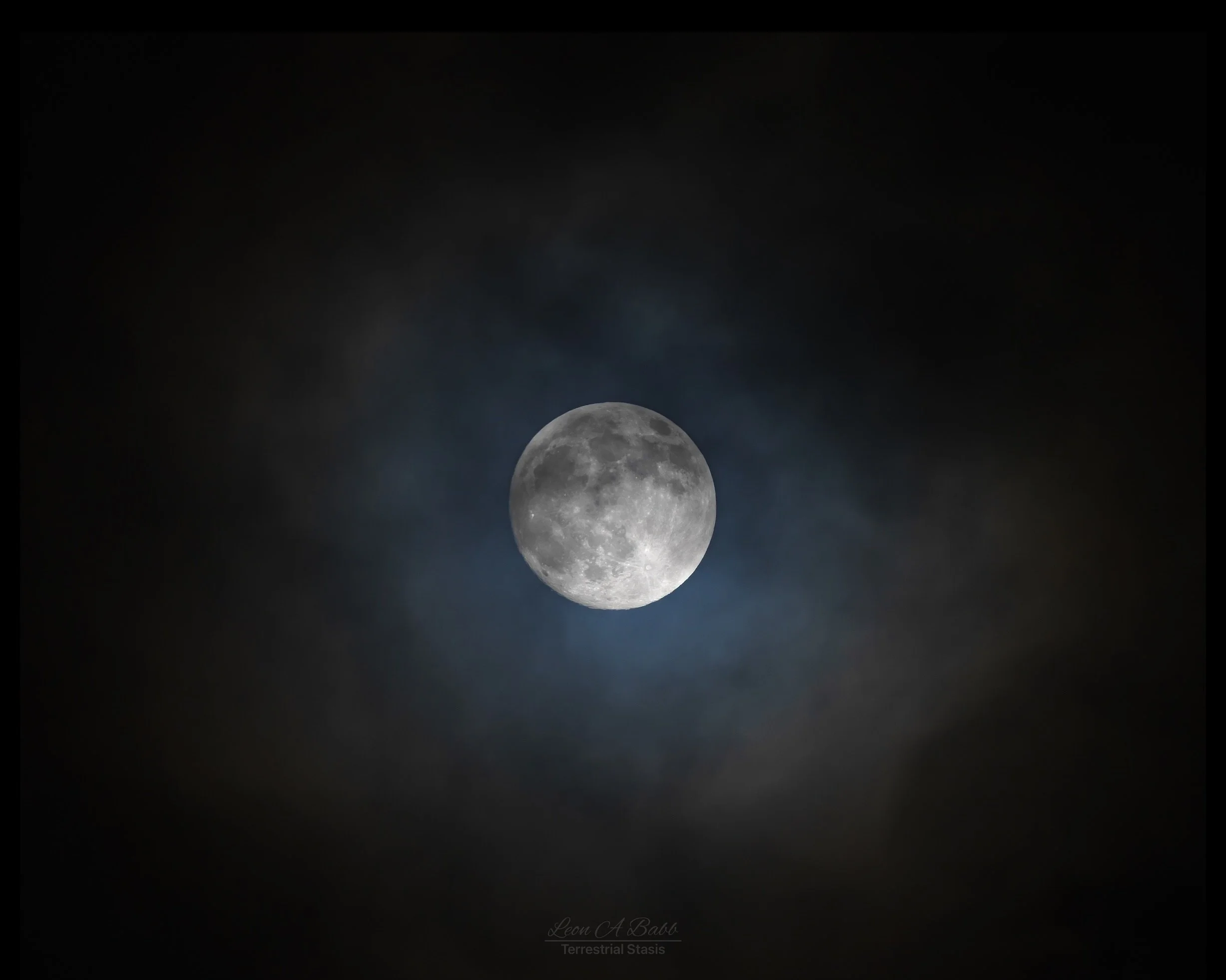 Photograph of the moon surrounded by a dark sky and faint clouds.