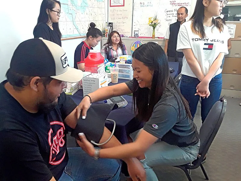Student volunteers conduct blood pressure checks of WFWA members