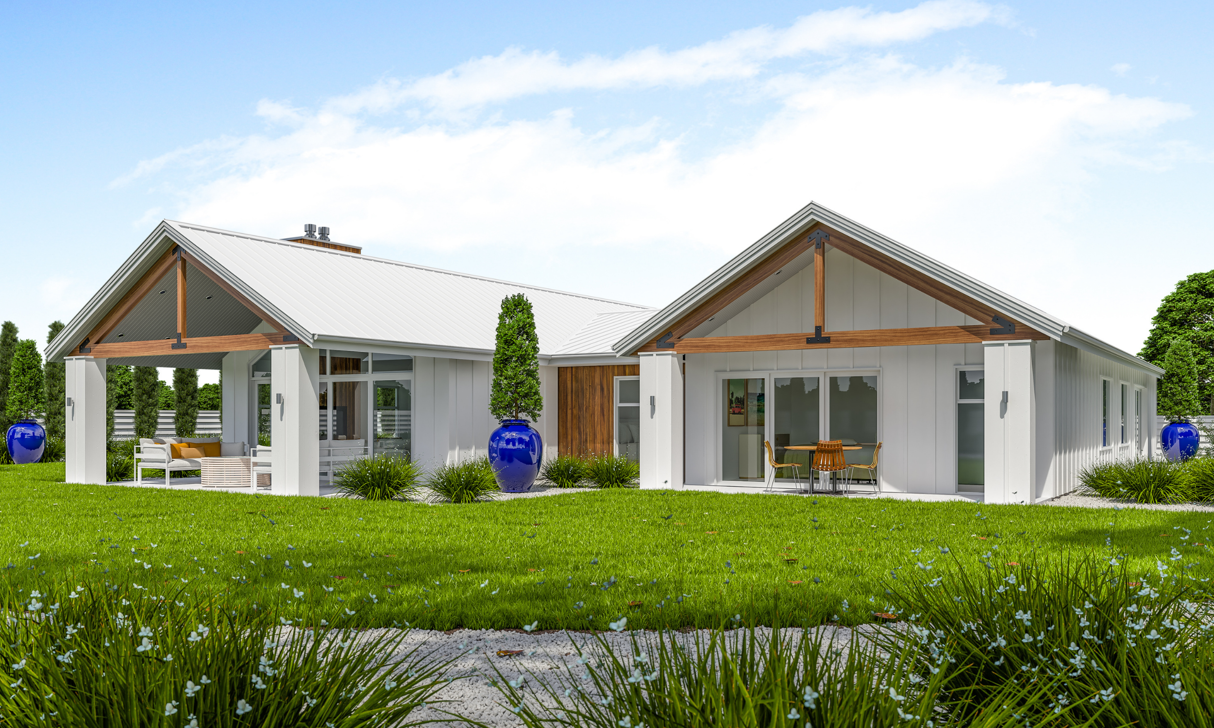 Modern white house with a metal roof, large windows, and outdoor seating areas, surrounded by green grass, blue vases with plants, and a clear blue sky.