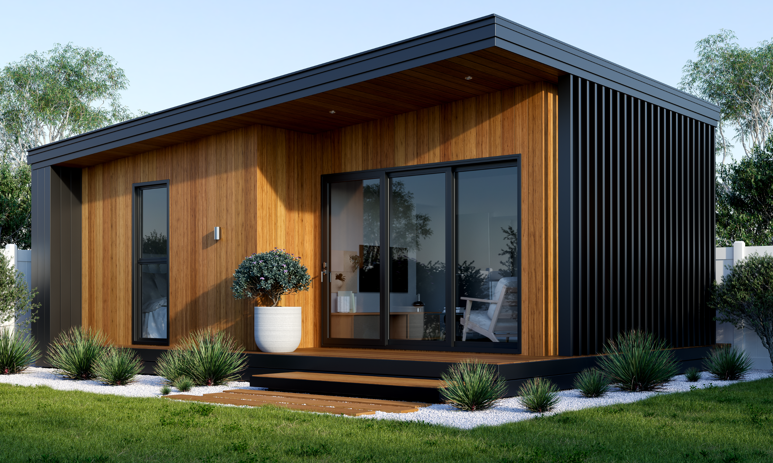 Modern tiny house with wood and black siding, large glass sliding door, small porch, potted plant, surrounded by greenery and trees.