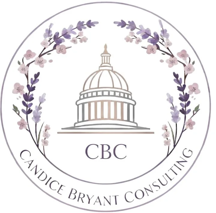 A circular logo featuring a pastel purple and pink floral wreath surrounding an illustration of the U.S. Capitol building with the initials 'CBC' underneath. The text 'Candice Bryant Consulting' is curved along the bottom inside the circle.