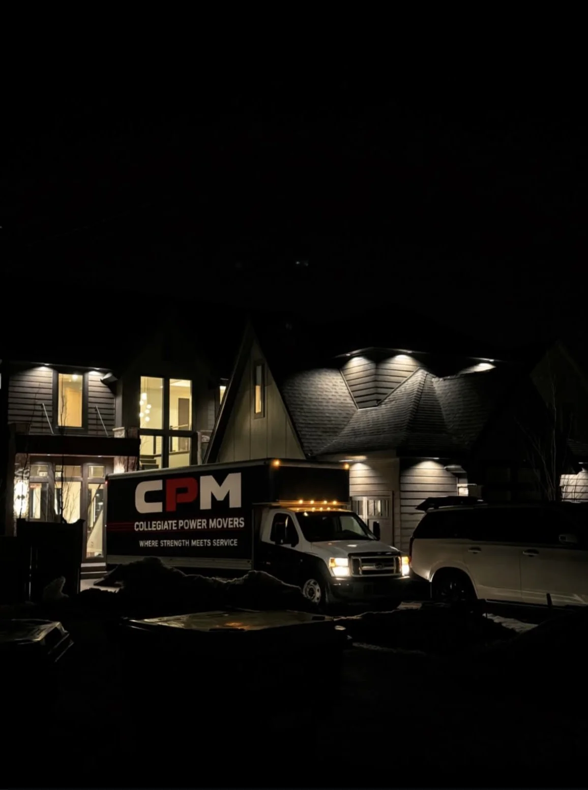 A person loading items into a moving truck outside an apartment building on a clear day.