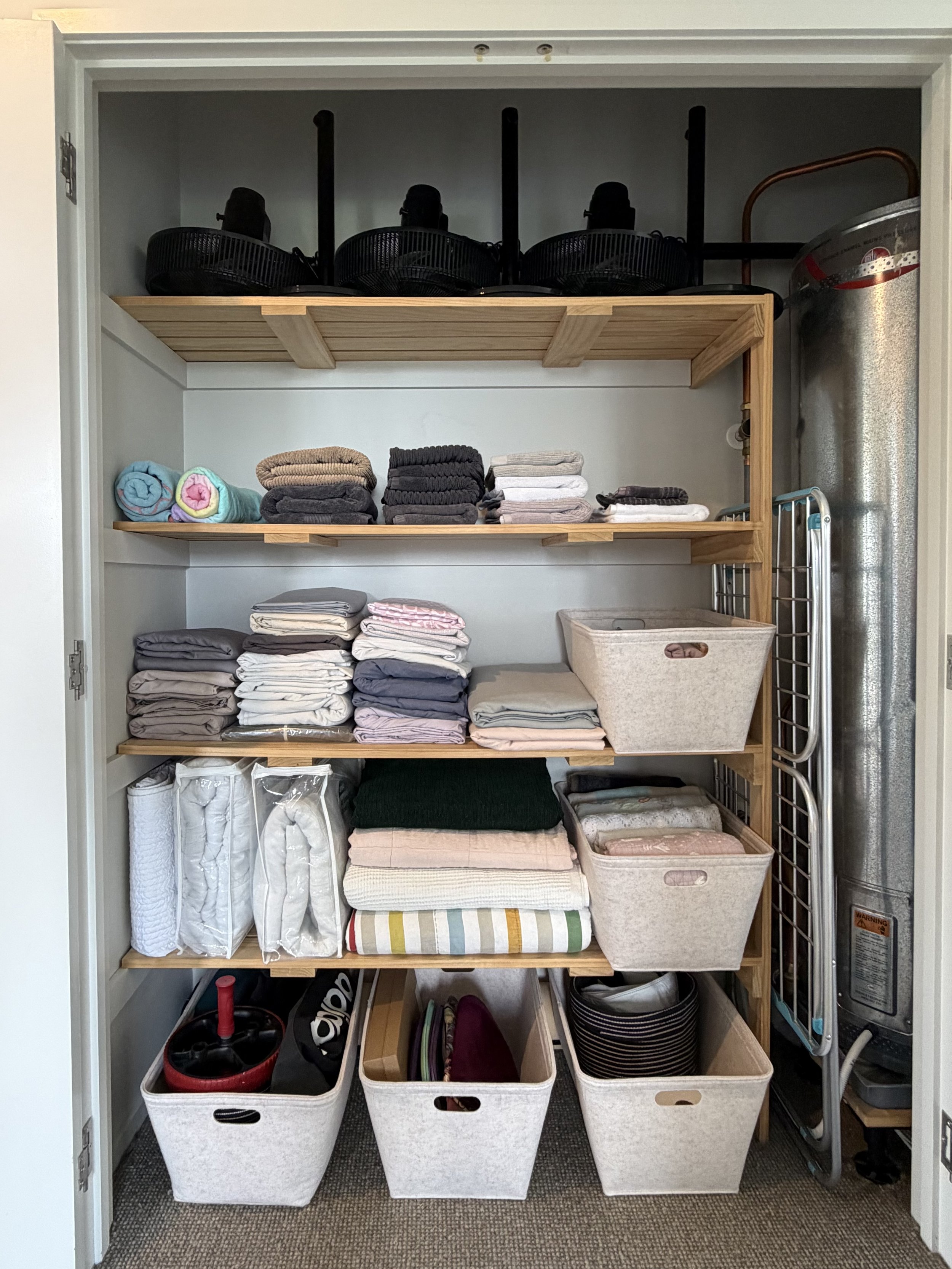 After linen cupboard transformation by Spaces by Kat in Auckland, featuring neatly folded towels, organised bedding and coordinated storage baskets.