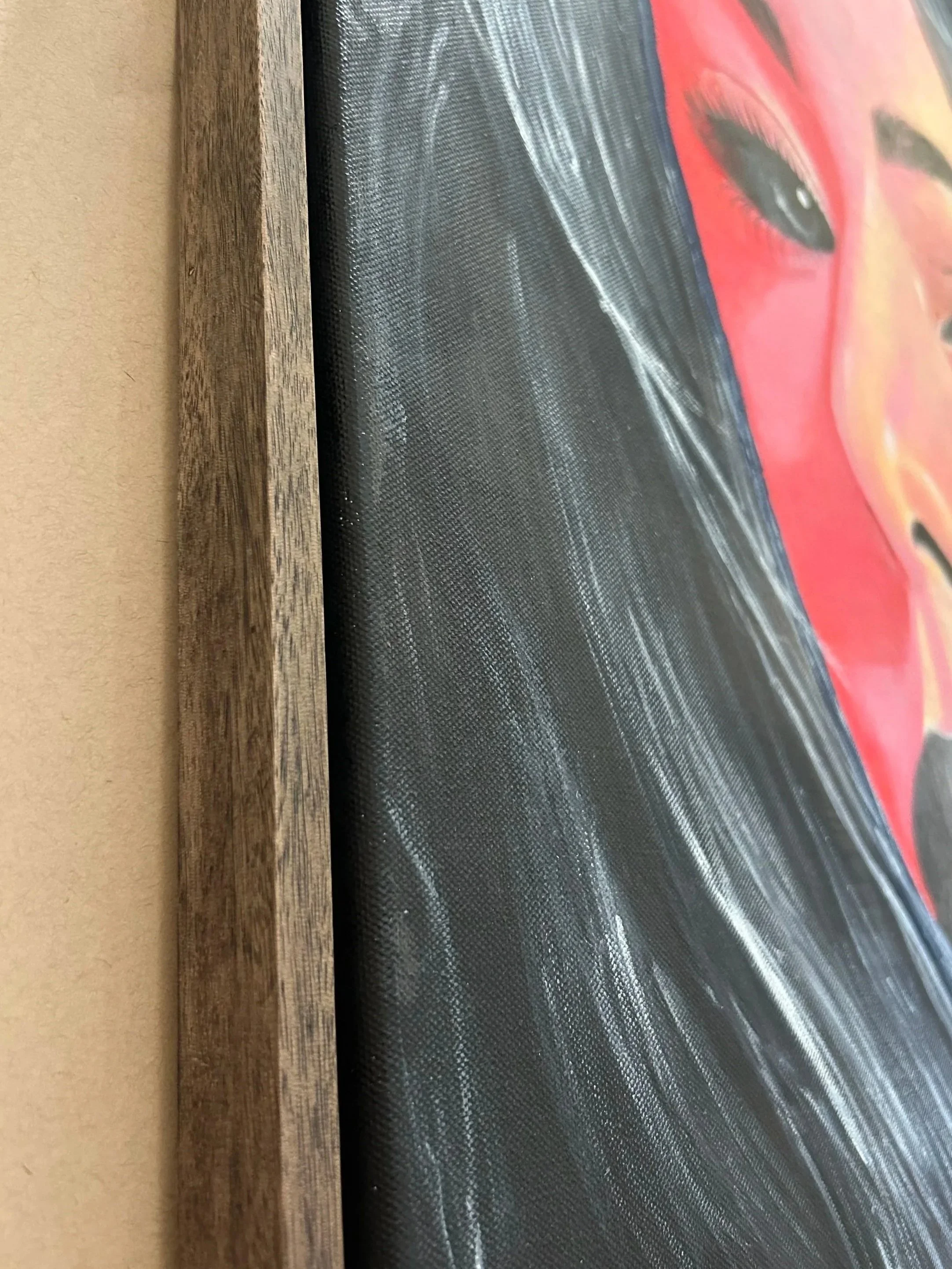 Close-up of a framed artwork depicting a person's face, with a focus on the eye, on a black background.