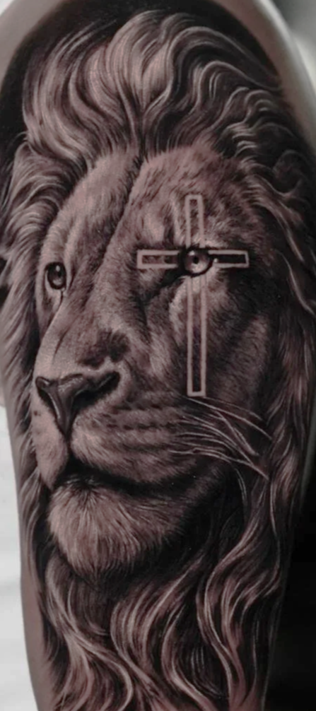 Tattoo of a lion's face with a cross-shaped scar around one of it's eye on a person's arm. Tattoo done by Allan Mandi realism tattoo Artist from Knoxville Tennessee